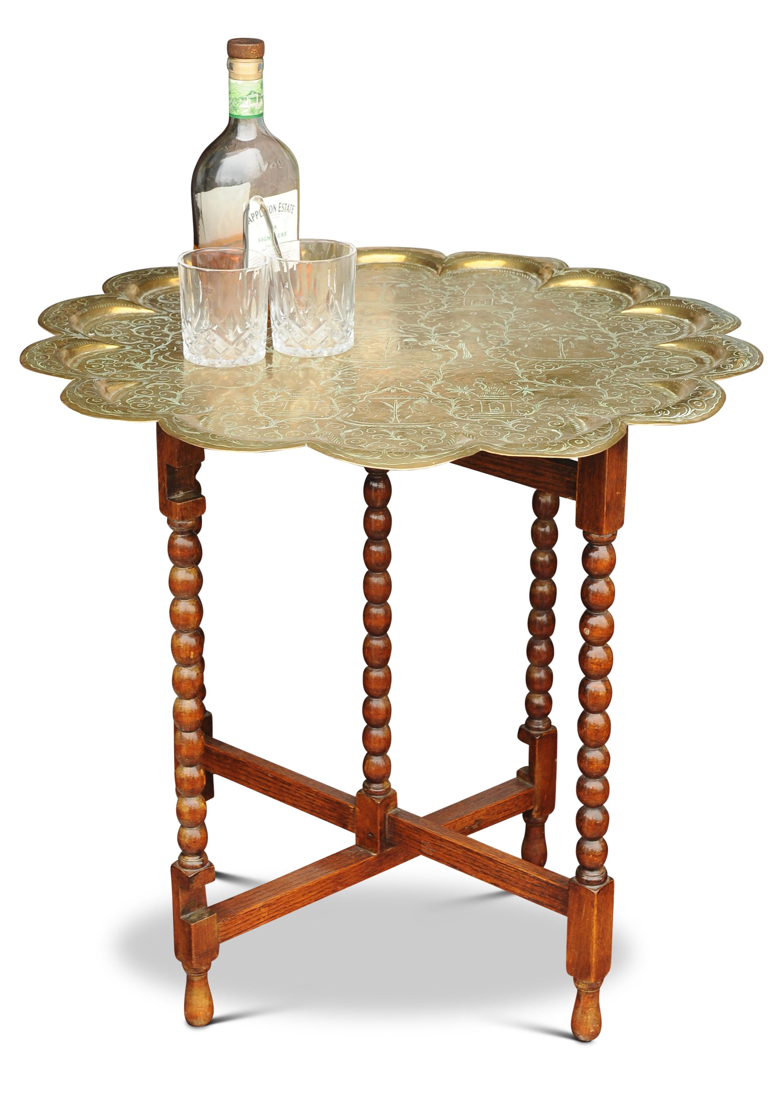 A Beautiful and Unusual Brass Etched Tea Table Featuring Two Tiered Brass Trays, With An Oak Bobbin Gate Legged Folding Table 

Both Trays Can Be Removed To Serve Drinks, & Both Trays Have Engraved Depictions Within Their Pie Crust Edges.

Trays can