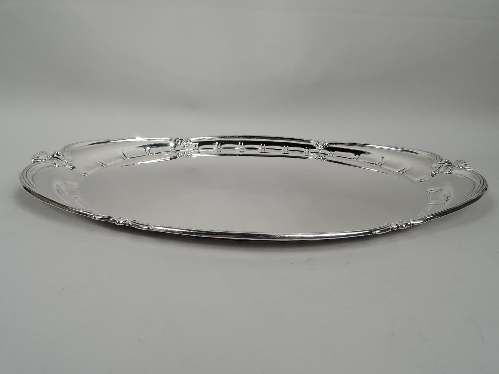 Elegant Edwardian classical sterling silver tray. Made by Tiffany & Co. in New York. Oval well with lobed and stylized border. Rim reeded, asymmetrical, and lobed inset with leaves, scrolls, and covered vases. Fully marked including maker’s stamp,