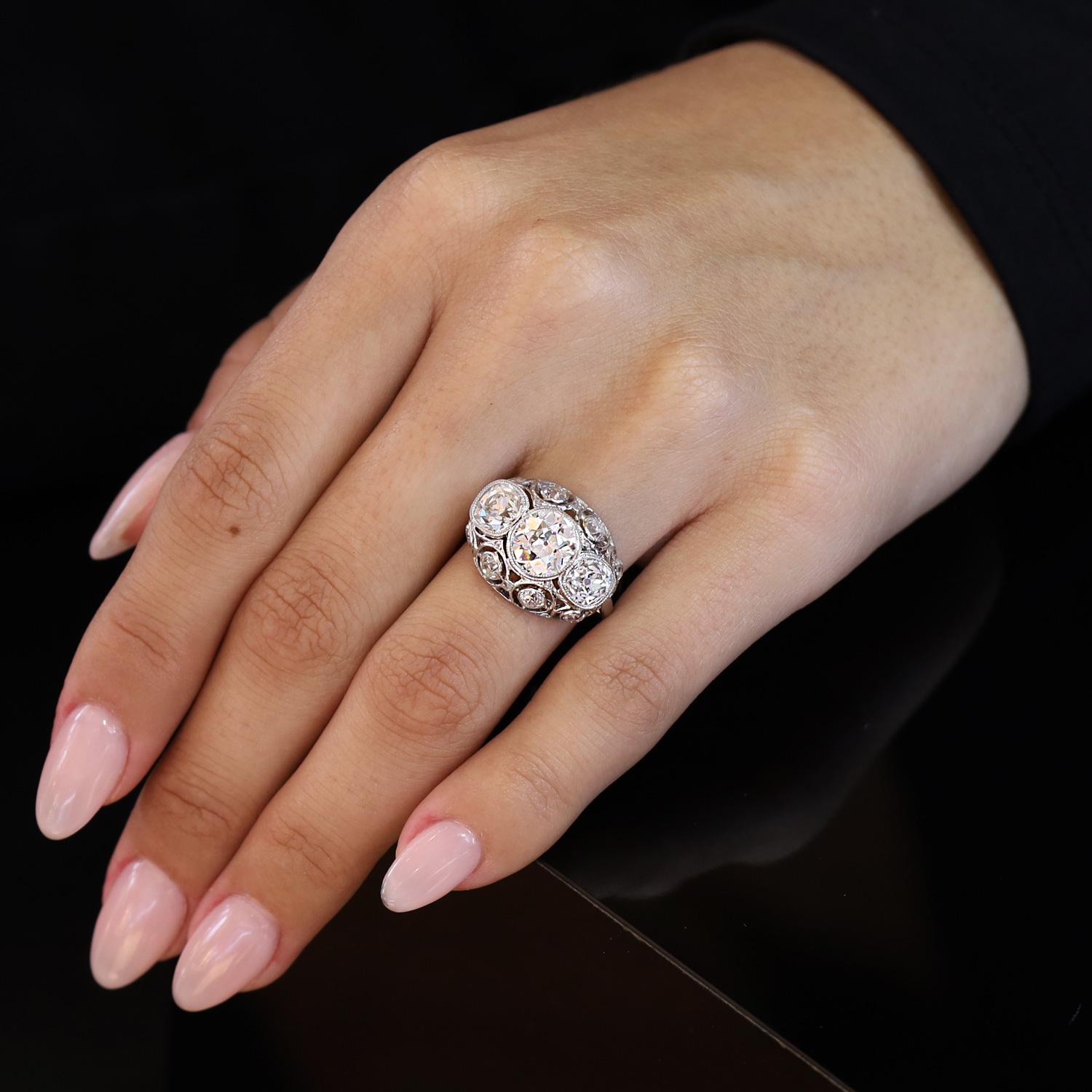 Elegando l'eleganza dell'epoca edoardiana, questo magnifico anello di fidanzamento con 3 pietre di diamante certificato GIA offre un'affascinante visione del passato. L'incastonatura bombata, unica nel suo genere, è impreziosita da una dettagliata