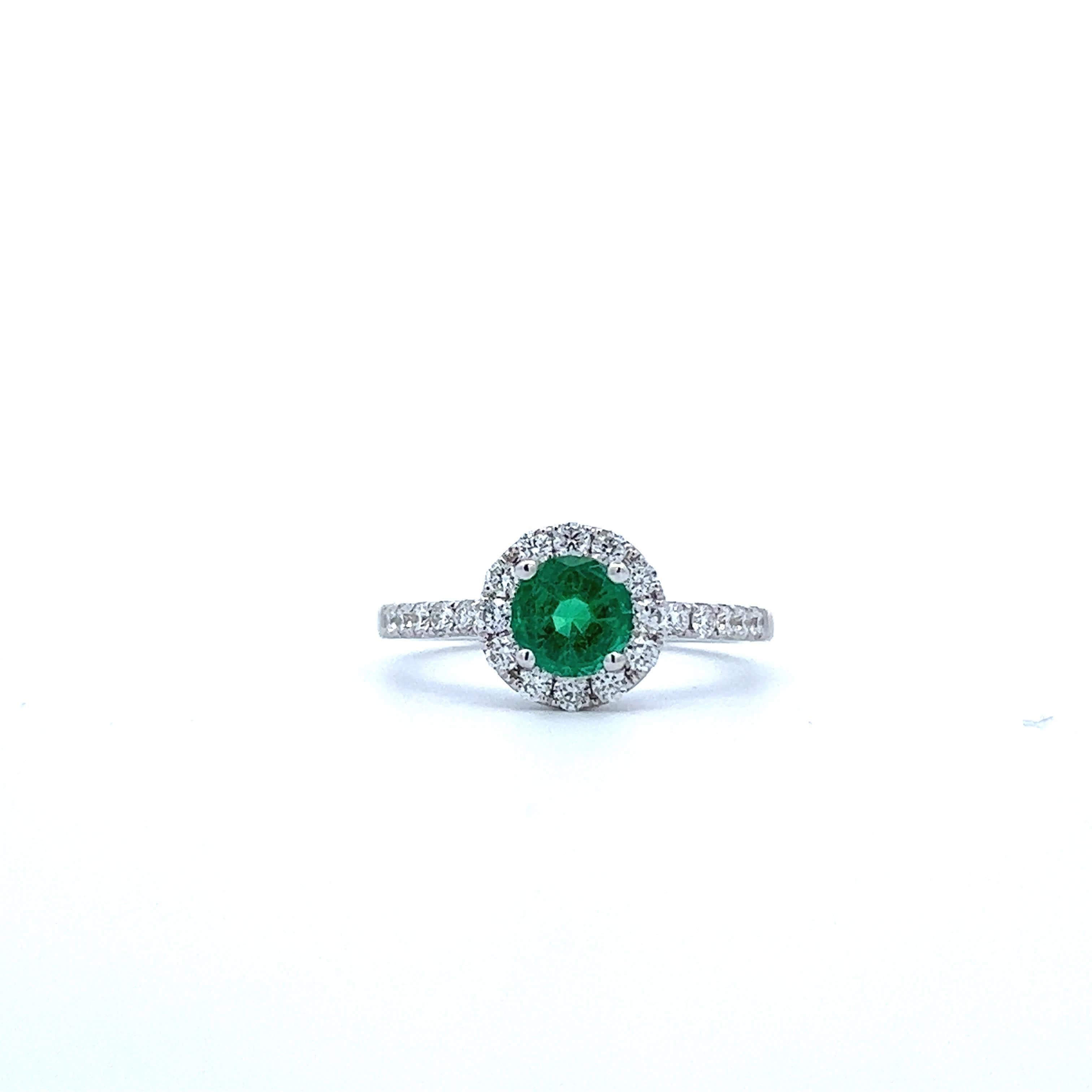 Entdecken Sie die Anziehungskraft dieses atemberaubenden Smaragdrings, der von einem Heiligenschein aus funkelnden Diamanten umgeben ist. Der leuchtend grüne Stein zieht die Blicke auf sich und macht ihn zu einem perfekten Schmuckstück für jede