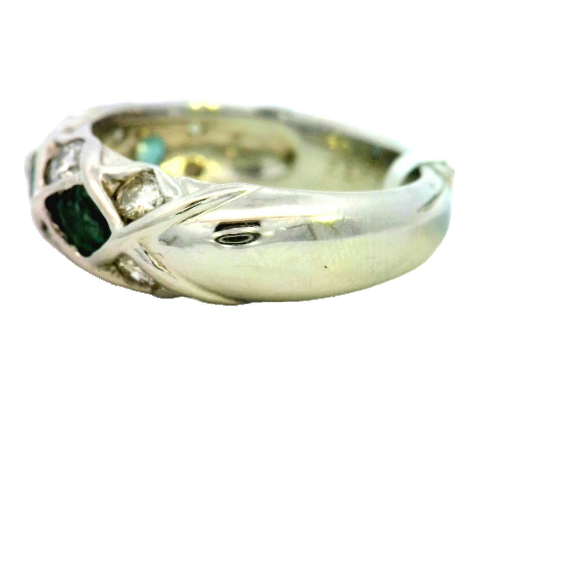 Entdecken Sie die exquisite Schönheit dieses Rings mit Smaragd und Diamanten, der Sie in seinen Bann ziehen und bezaubern wird. Das verschlungene Band besteht aus einem atemberaubenden Arrangement leuchtend grüner Smaragde, die mit funkelnden