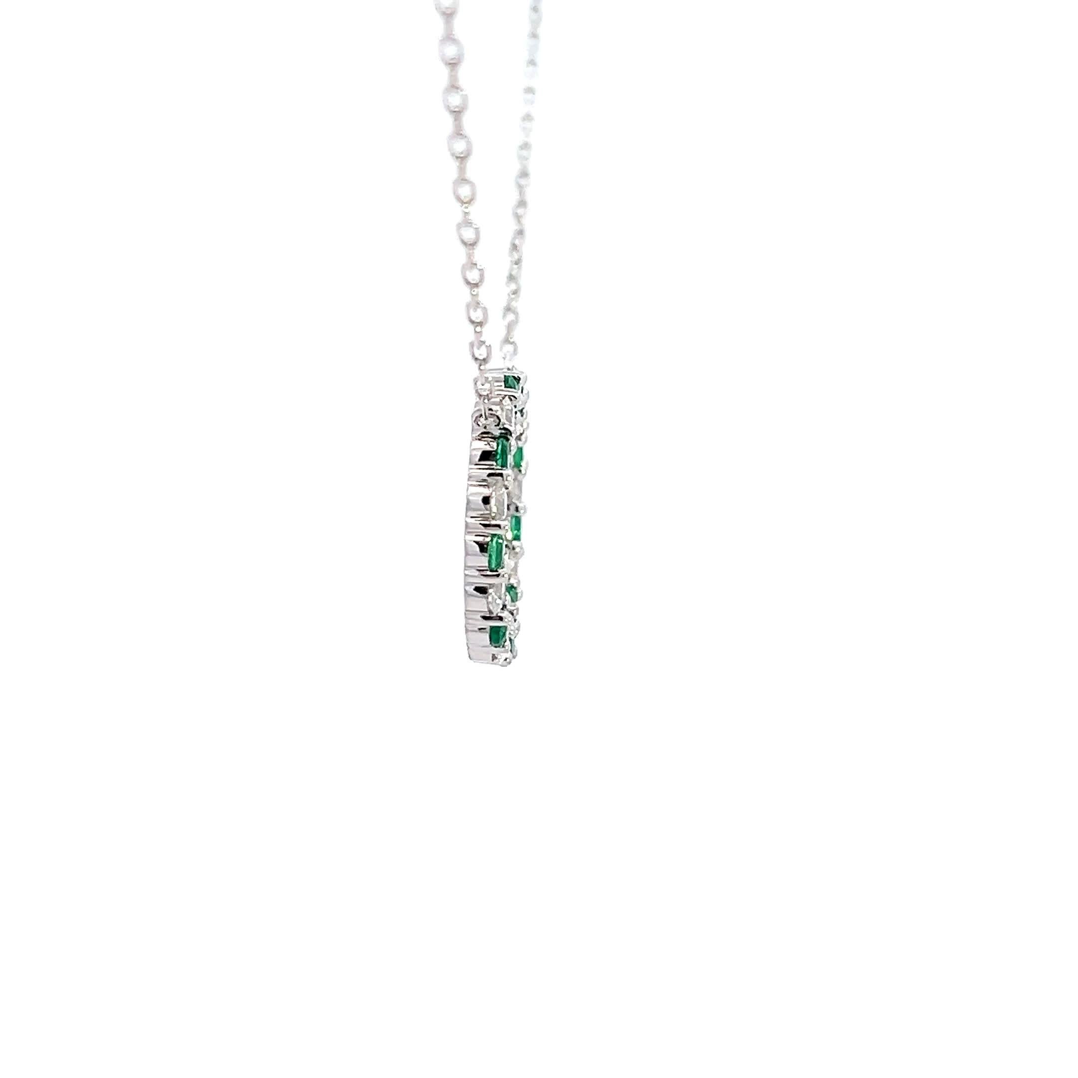 Ce pendentif exquis présente un cercle délicat orné de pierres alternant émeraudes et diamants, serties dans de l'argent sterling. Son design élégant est parfait pour ajouter une touche de sophistication à n'importe quelle tenue.