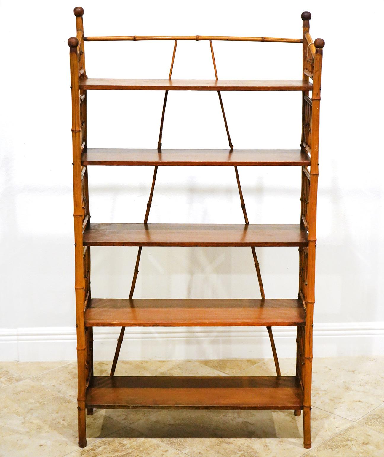 This early 20th bamboo bookshelf features a bamboo framework with mahogany shelves. The design creates a British colonial flair. The two angled bamboo rods create structural rigidity as well a an aesthetic effect.