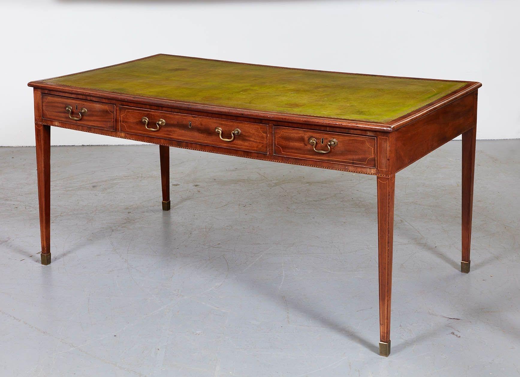 English late 18th century/early 19th century mahogany writing table with hand-tooled leather top on three drawers standing on tapered legs ending in brass capped feet, with fine string inlay to apron, drawers and feet. Wonderfully grained mahogany,