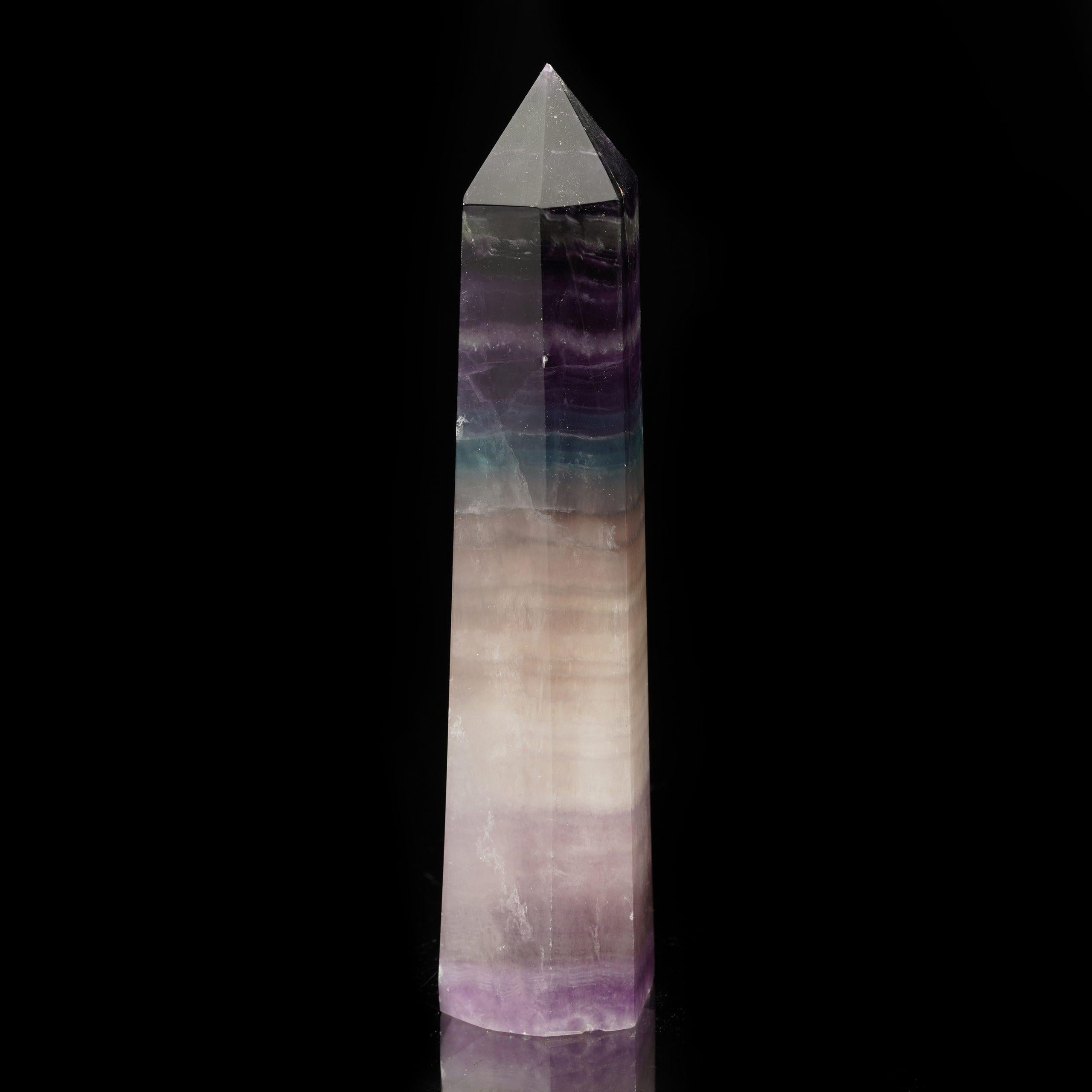 This refined Fluorite obelisk originates from China, a well-known source of exceptional mineral formations. The piece features the captivating natural colors that Fluorite is famous for, with subtle banding and translucent areas that catch the light