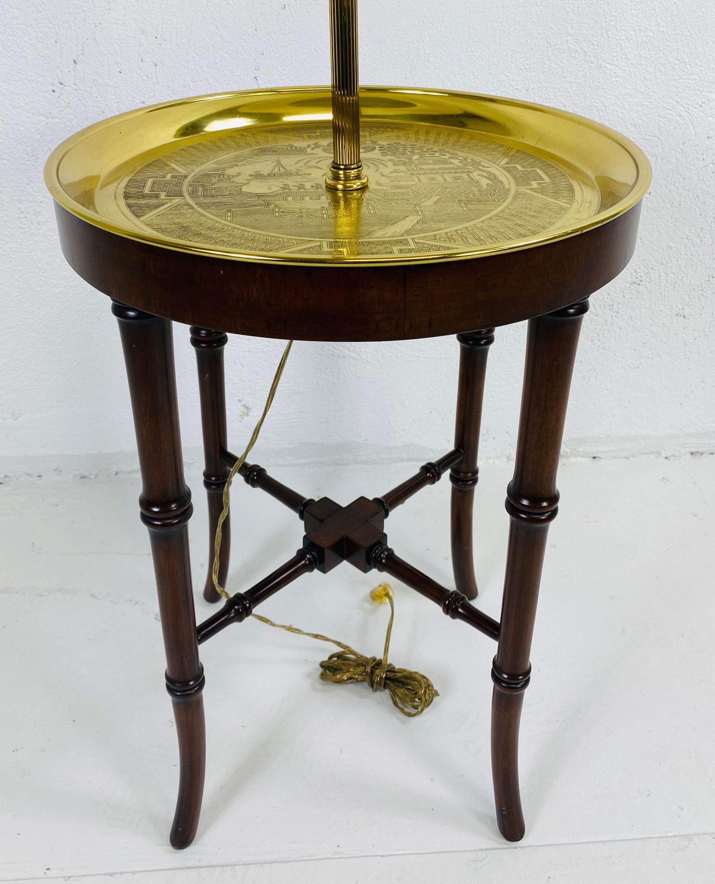 This is an elegant Frederick Cooper chinoiserie style floor lamp. This floor lamp features a faux bamboo Regency style walnut table base with an elegant brass tray. The brass tray features Chinese scenes engraved into the highly polished brass. The