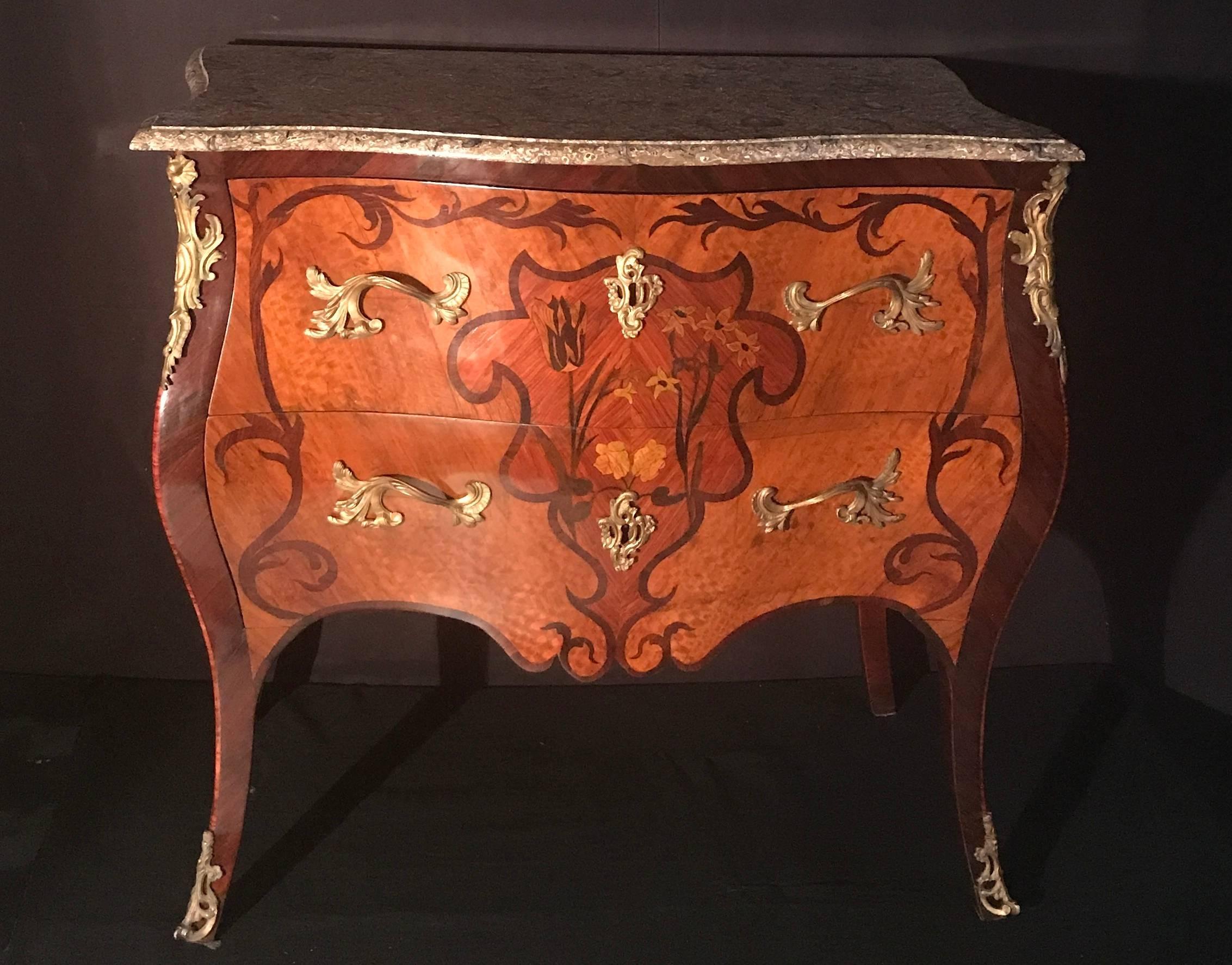 With 'Lumachella' marble-top above two drawers decorated sans travers and ormolu mounts.
Fine detailed floral inlay with various noble woods. Finely chiseled and gild original bronze fittings.