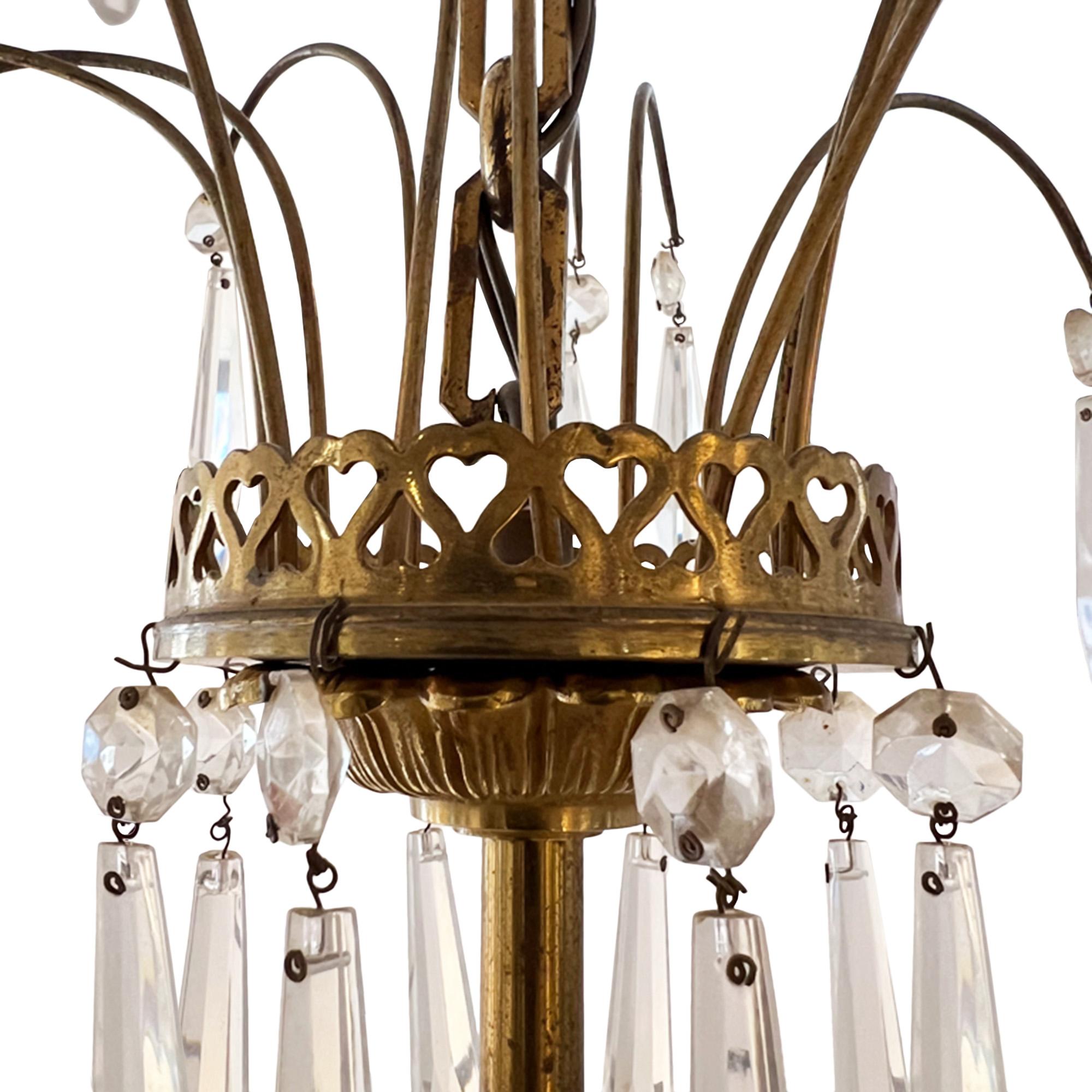 This unusual chandelier was made in France in the 1950s.

Please take a look at all our pictures - the elegantly simple design has lovely touches of detail. From the lovely hearts decorating the top piece of gilt bronze, while leaves decorate the