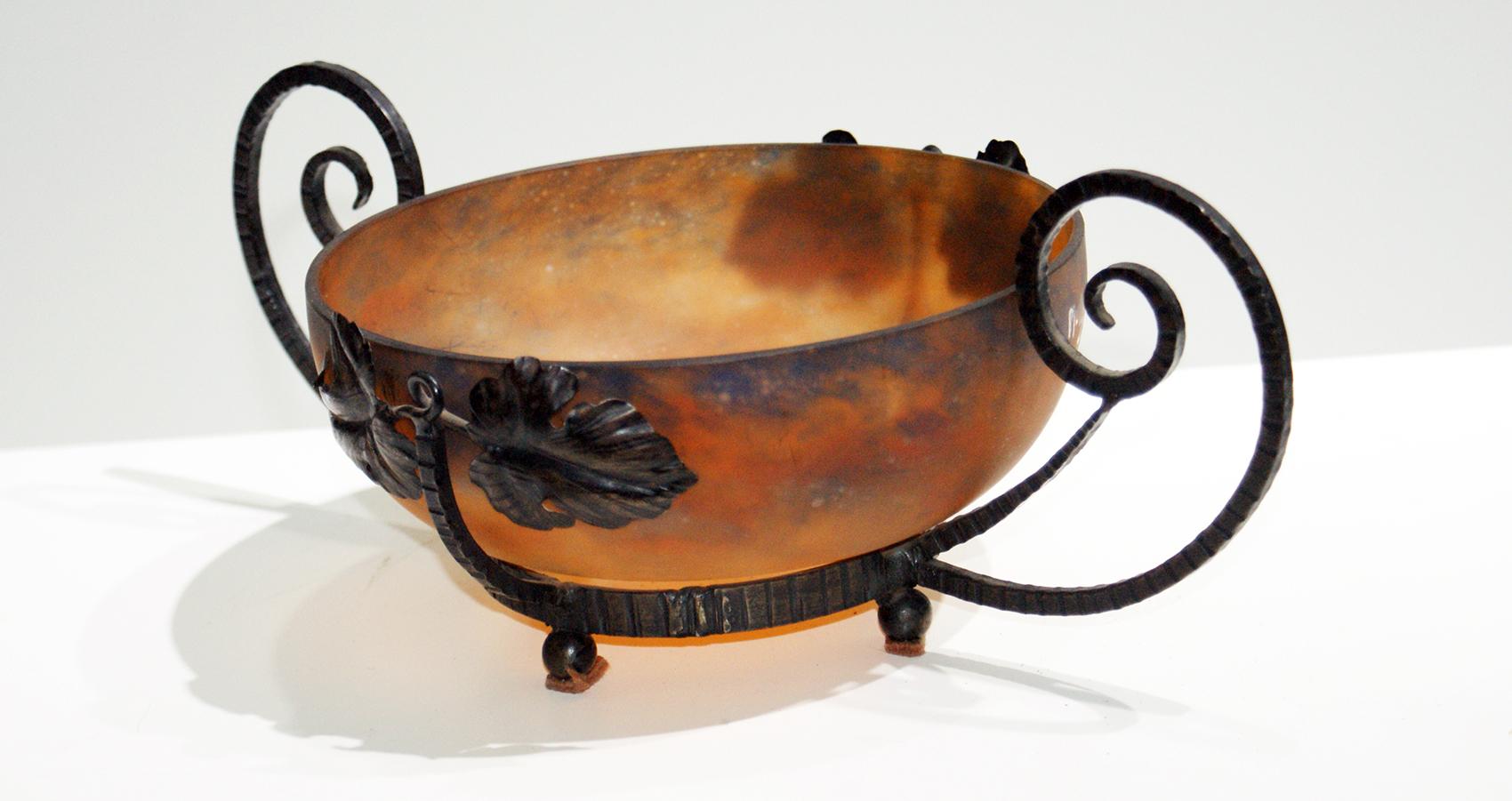 Art Deco bowl made of molten glass “Pâte de verre” and wrought iron. The wrought iron carrier is decorated with leaves and geometric motif and is made in the style of “Louis Majorelle”.
The coupe has a mix of blue and orange colors.
This piece is