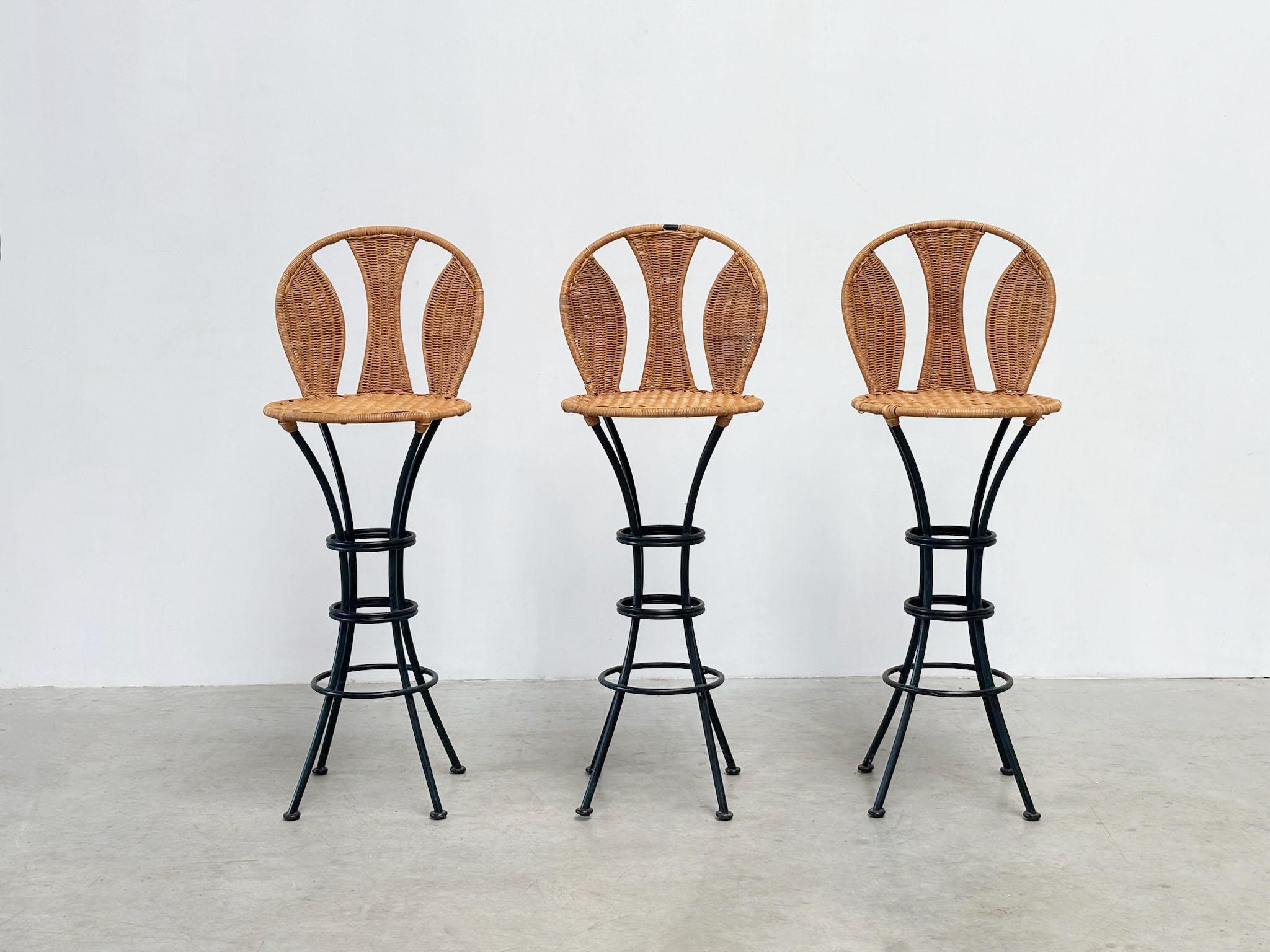 Un ensemble élégant de trois tabourets de bar français des années 1970, avec d'élégants dossiers et sièges en rotin associés à des structures en acier épurées. Le rotin chaud ajoute de la texture et du caractère, tandis que l'ensemble uniforme de