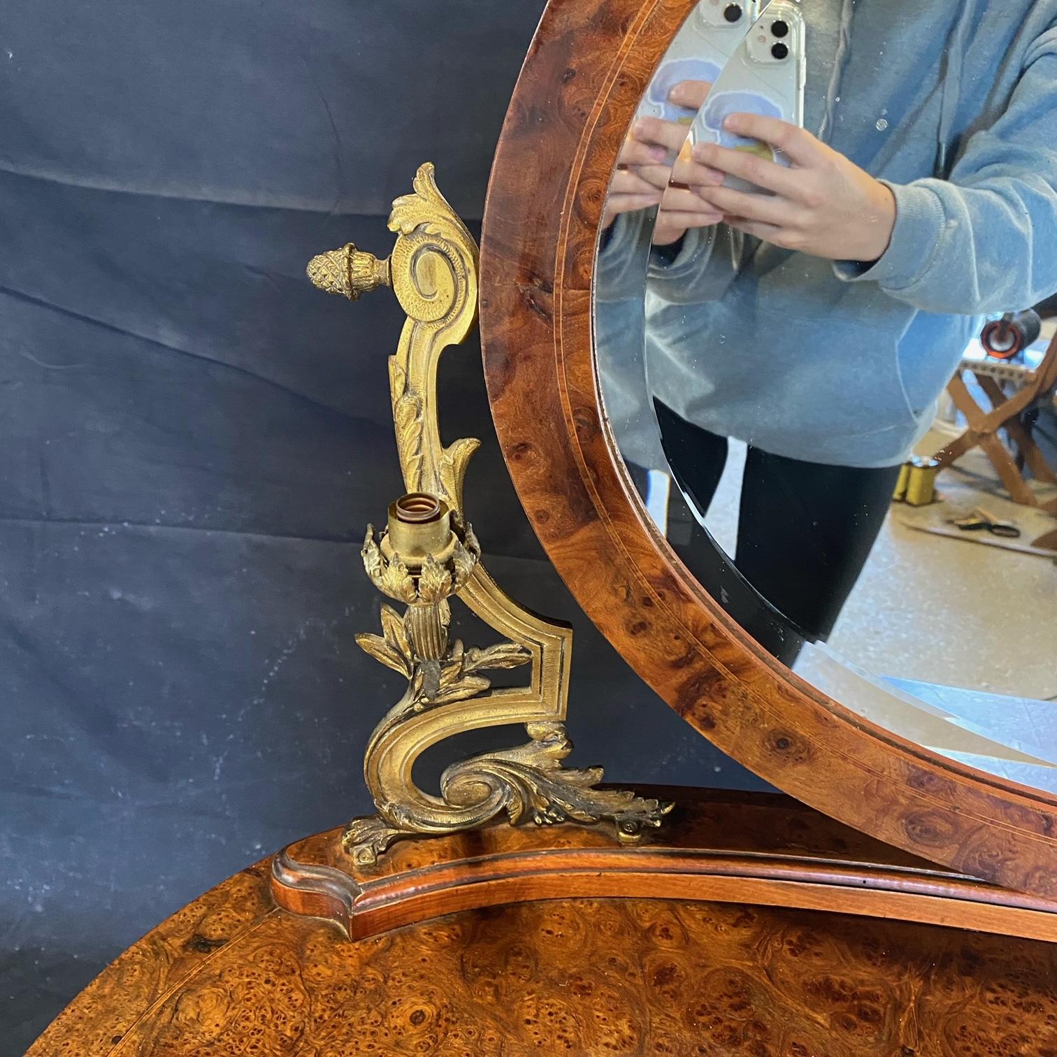 Stunning French burled walnut dressing table with beveled mirror having side mounted bronze candelabras and acorn finial mirror supports. Beautifully turned legs and bronze mounted feet. Center drawer with bronze ring pull. H of surface