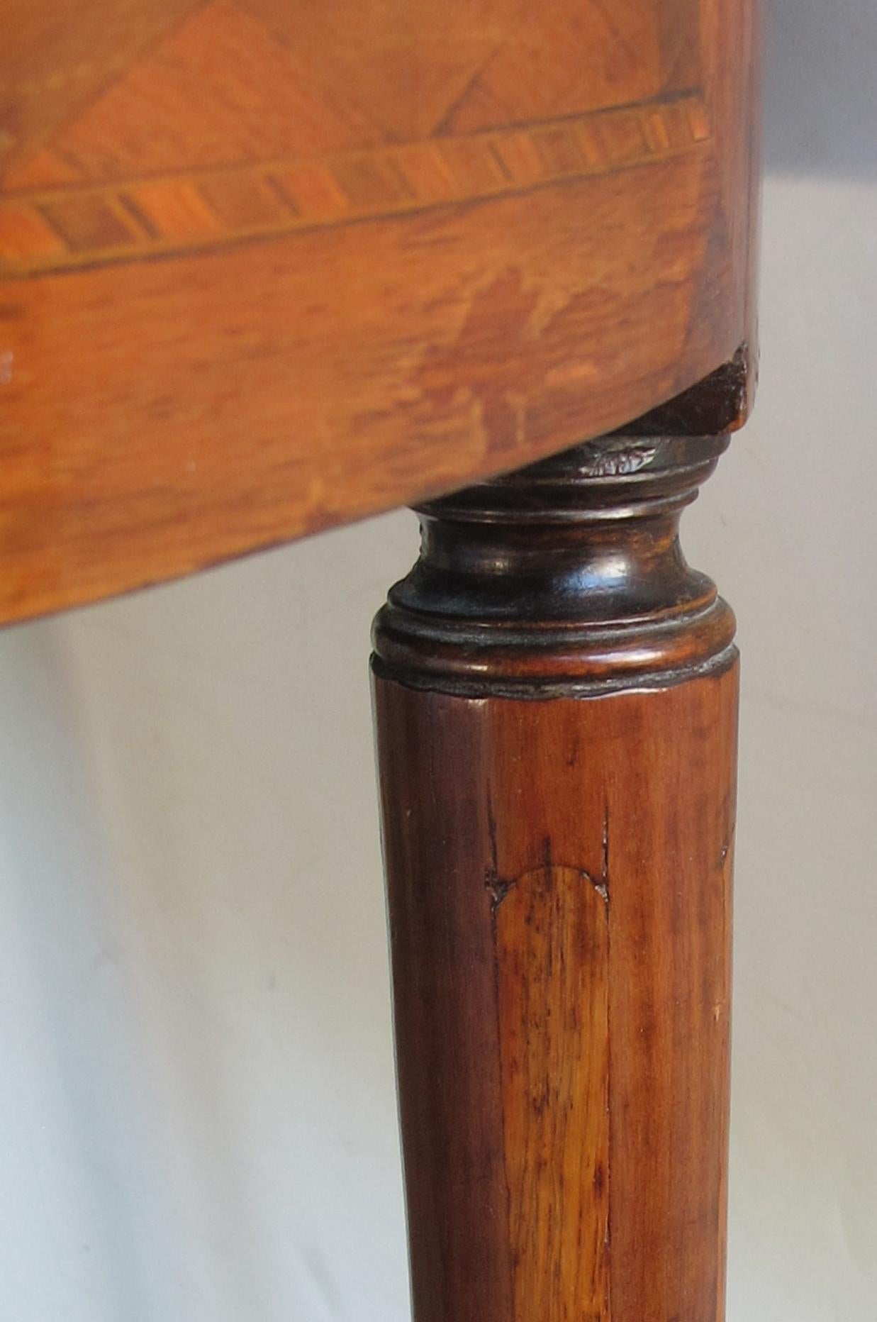 The marble top within a pierced brass gallery above an apron with chevron pattern veneer parquetry and fitted with 2 opposing drawers; raised on tapering turned legs ending in brass caps.