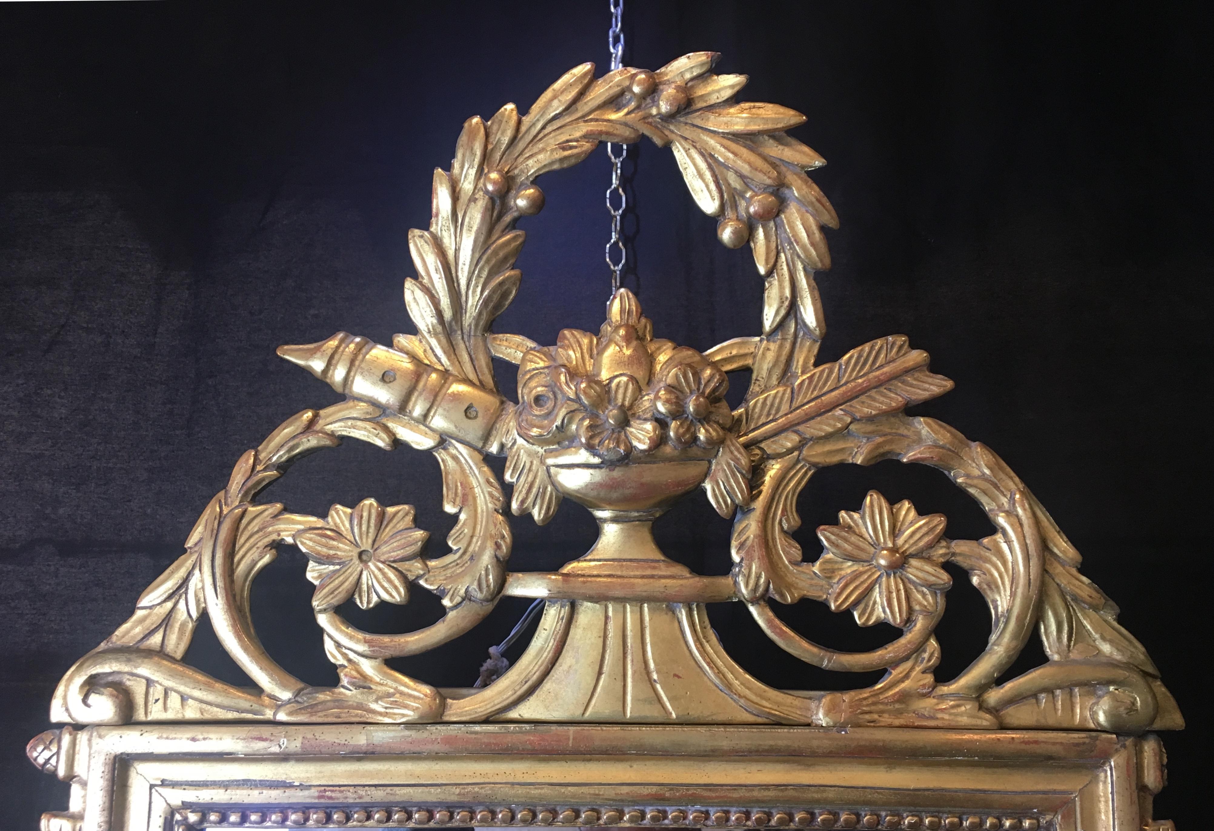 Louis XVI style hand carved, gilt wood mirror with a wreath pediment top.

This is a very high end vintage mirror, made in the early 20th century. 
Beautifully detailed in gold, the mirror has solid wood construction. 
 