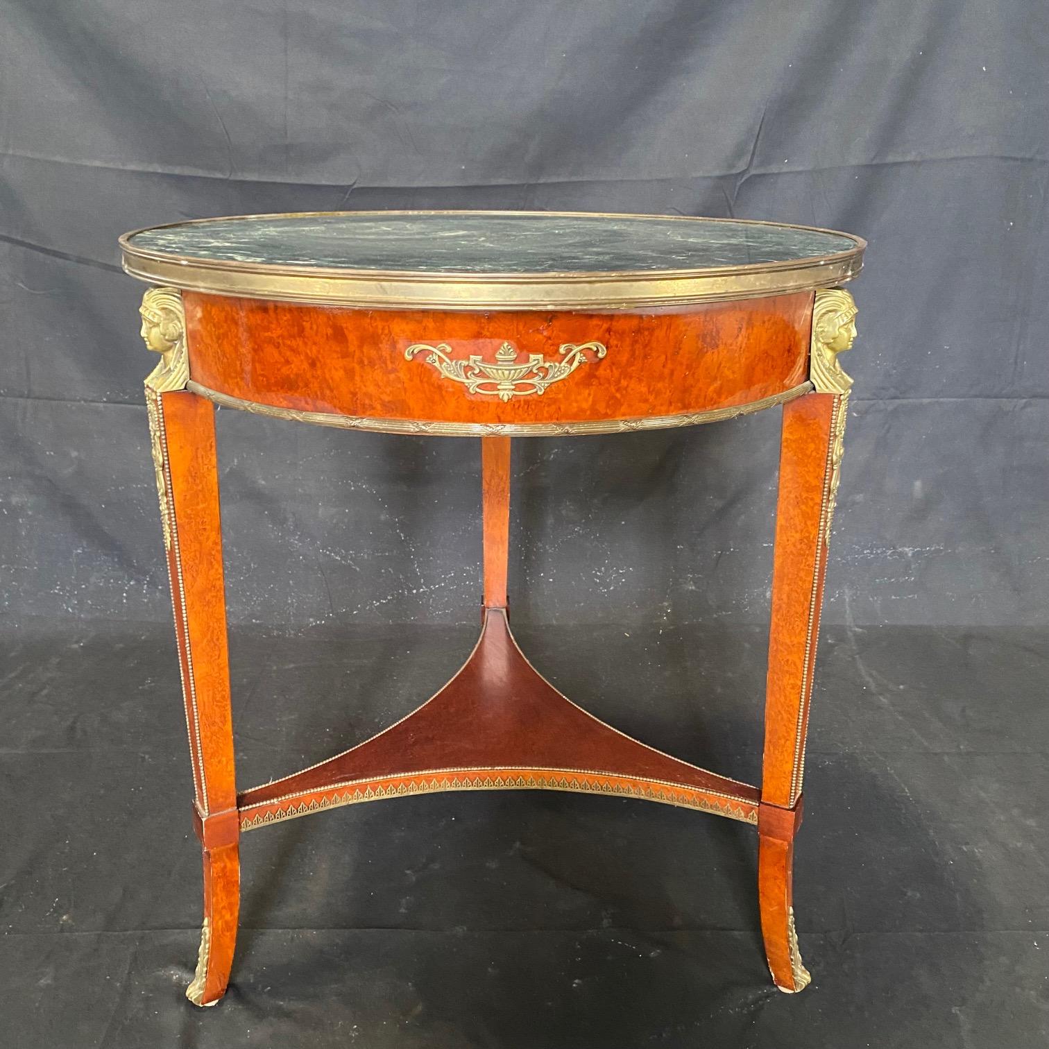 Lovely French Neoclassical style round side table with beautiful green marble top over tapering legs capped with bronze jabots.  Exceptional details include figural busts in bronze and beaded trim as well as fretwork on the stretchers. Two of the