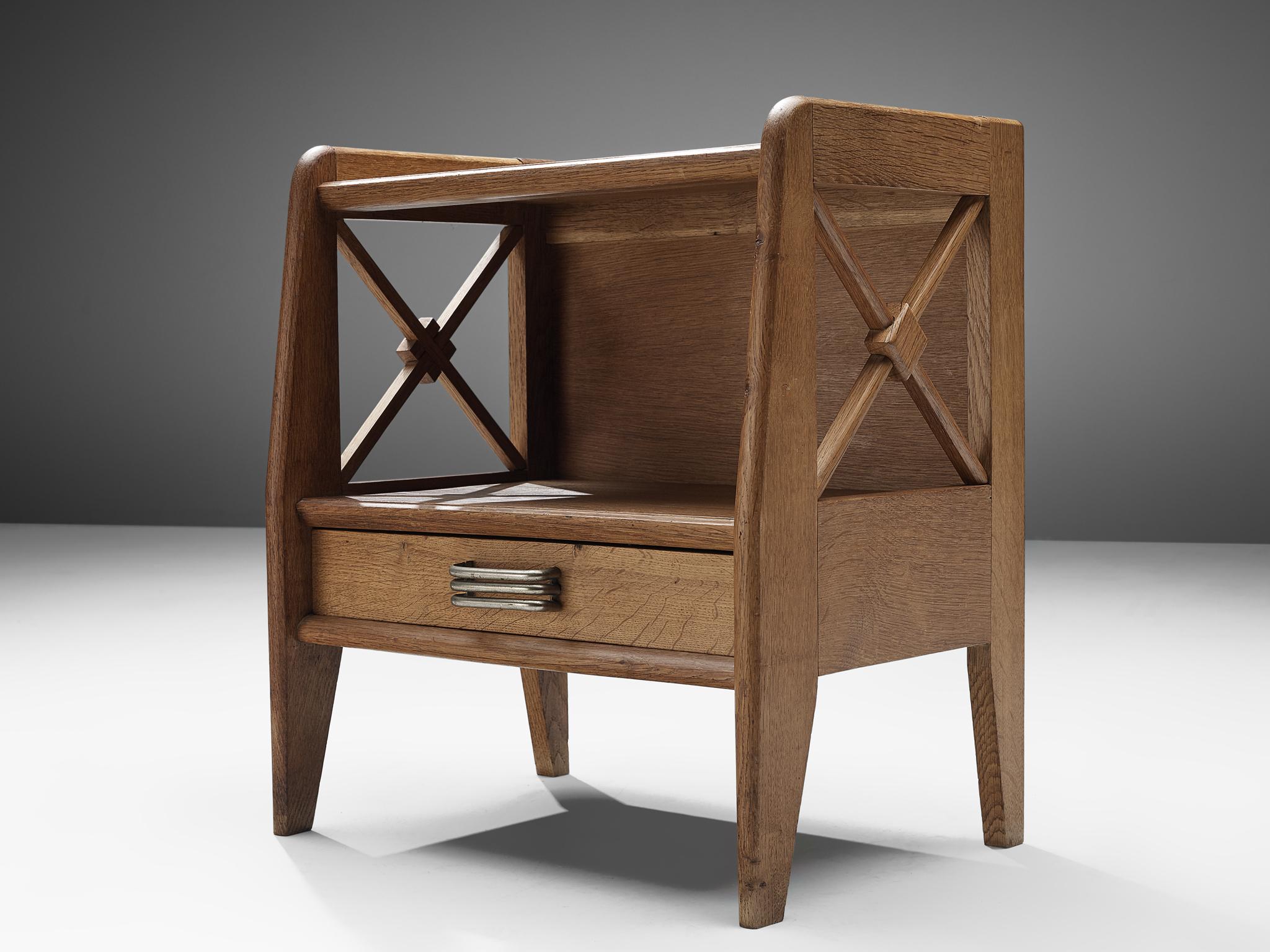 Nightstand, oak and brass, France, 1960s.

Elegant night stand in oak that feature geometric details on the sides. The nightstand is lifted from the ground by slim, conical legs that, together with the open character of the body, gives it a more