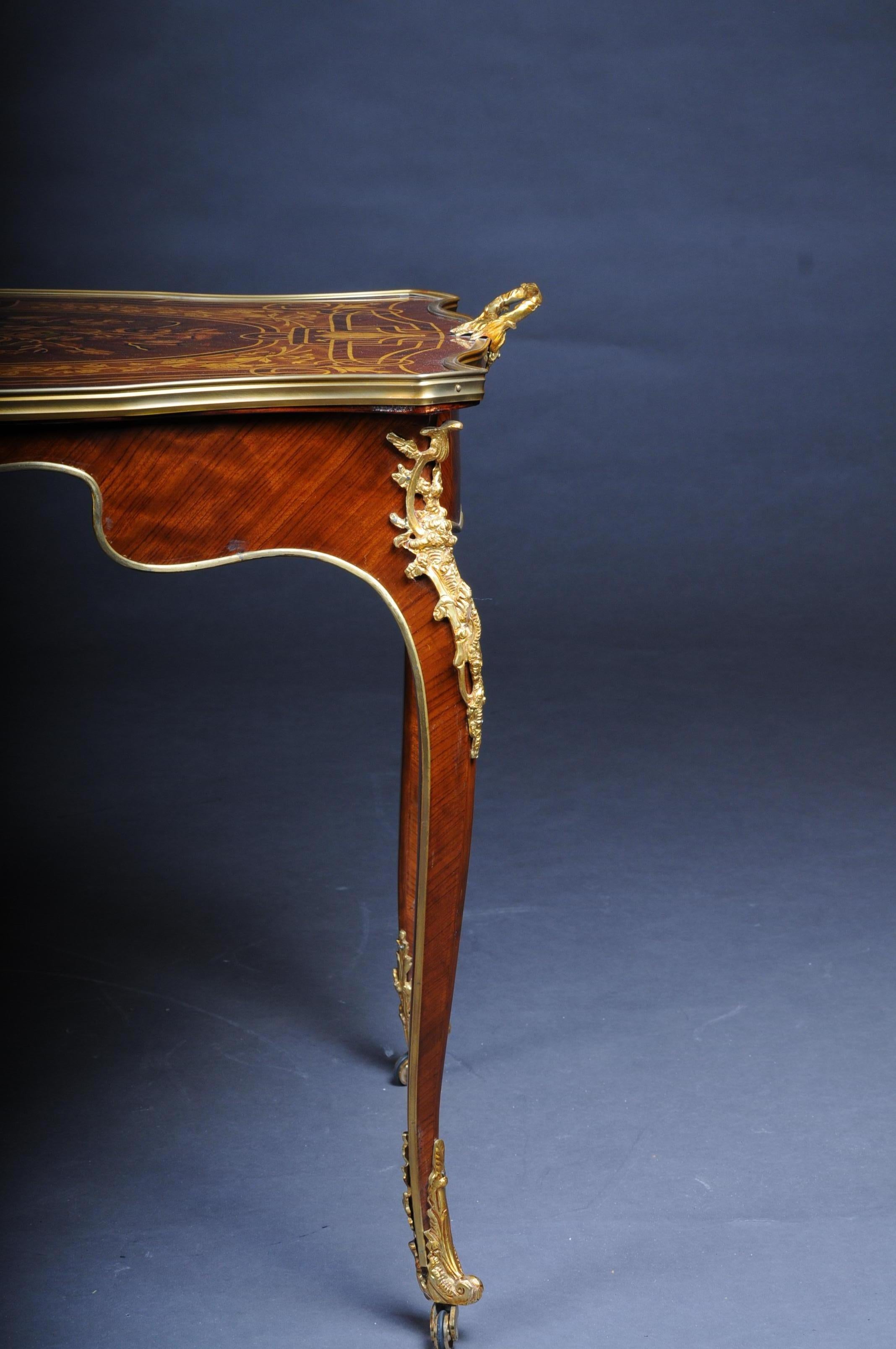 Elegant French salon table in Louis Quinze style.
Rose veneer on solid wood. Ending high, curved square legs in sabots. Slightly overhanging, framed in wide, matching profiles, tabletop with inset filigree maple inlays. Full-surface mirrored veneer