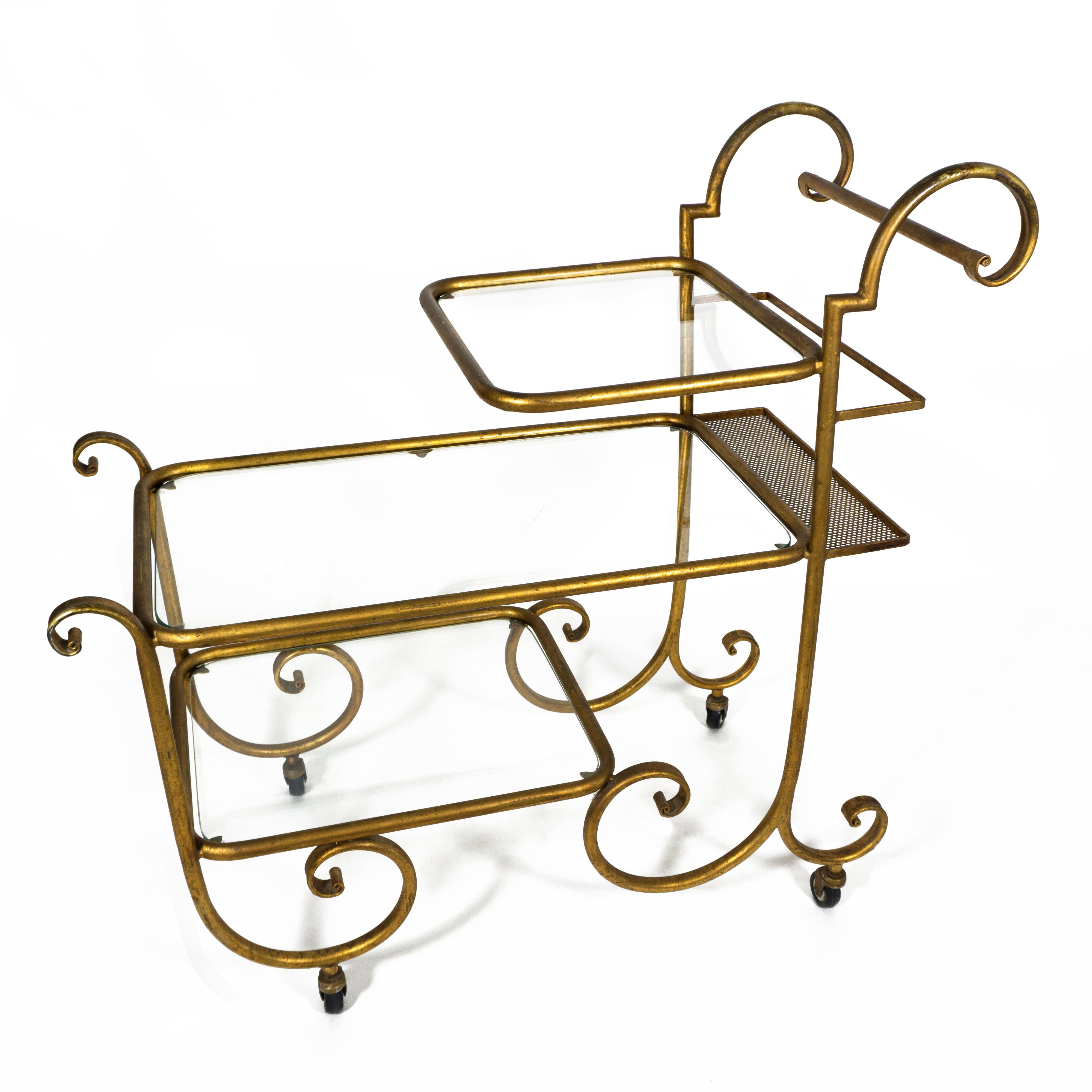 Beautiful Hollywood Regency trolley from the late 1960s early 1970s.
This elegant and very stylish gilded bar cart features two push handles, three tiers with glass top and for an extra touch of practicality a bottle holder is fitted to the upper,