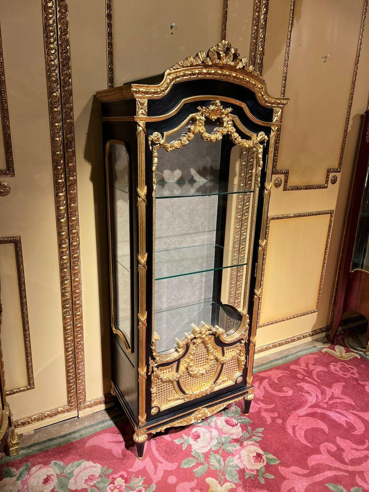 20th century elegant French Louis XVI style display case, black/gold beech Solid beech wood, frame in black/gold and partially gilded. Upright rectangular, three-sided facet-cut glazed, single-door body on conical legs. The front, corners and sides