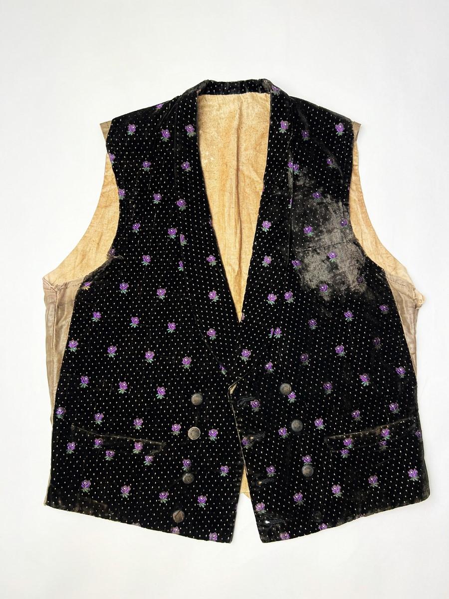 Circa 1860
France 
Elegant Second Empire waistcoat in black velvet embroidered with purple and green flowers and yellow dots. Shawl collar, cross-over fastening with eight embroidered buttons (one button missing). Original brown glazed cotton twill
