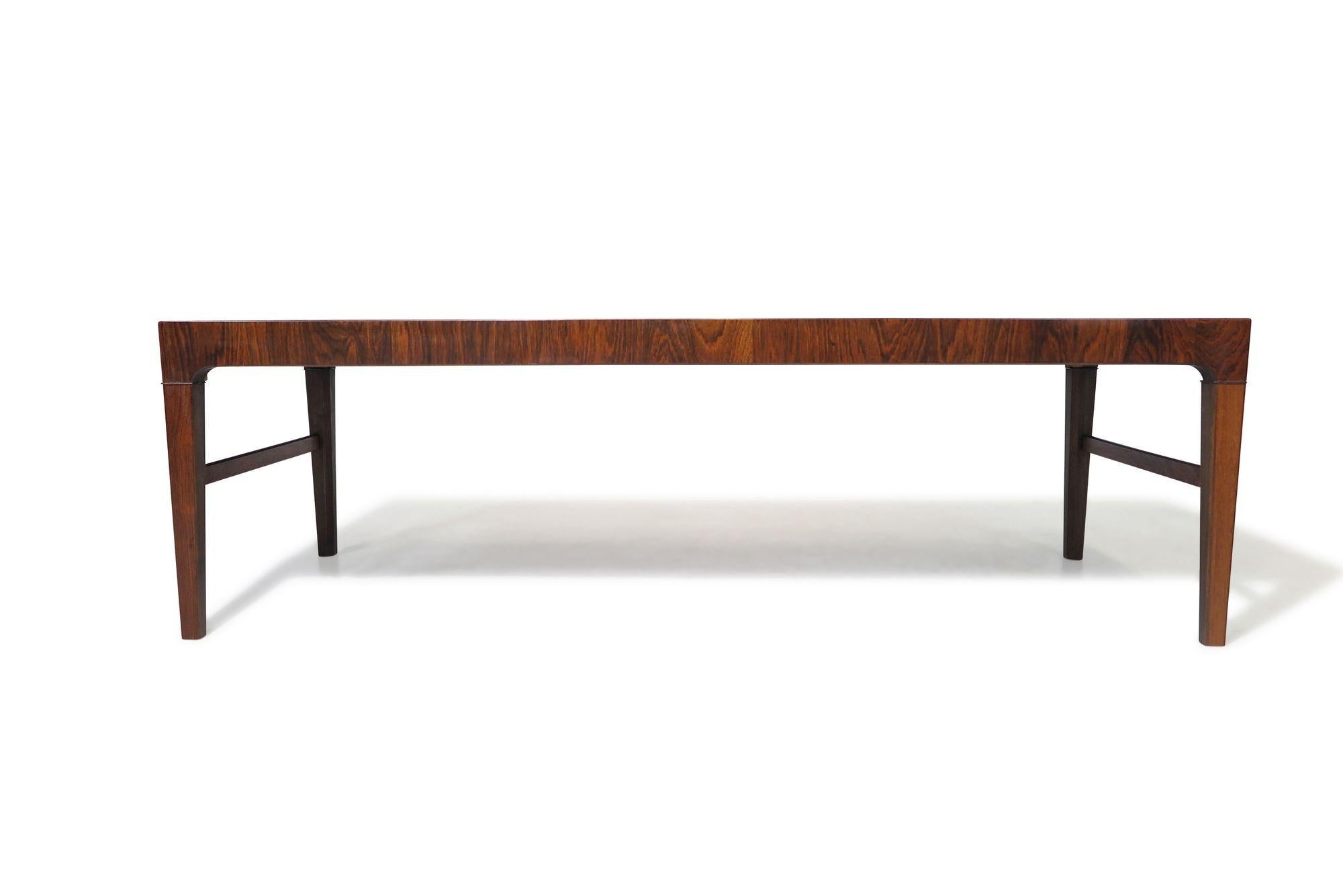 Elegant 1950's rosewood coffee table with stunning book-matched grain, in a rectangular form with tapered legs and cross stretchers, in the manner of master cabinetmaker Frits Henningsen.
Measurements
W 59'' x D 20,25'' x H 18''
