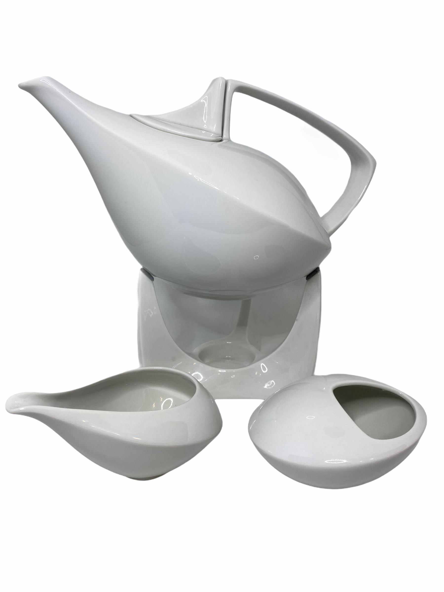 Elegante théière en porcelaine avec support, sucrier et crémier, support avec insertion pour bougie chauffe-plat. 
Dimensions : Théière : 5