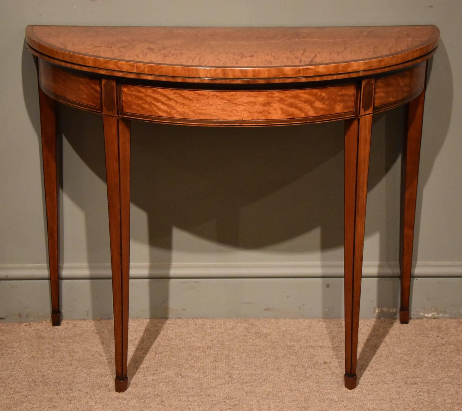 An elegant George III satinwood card table with purple heart crossbanding, of demilune form with purple heart borders and decoration.

Measures: Height 28.5