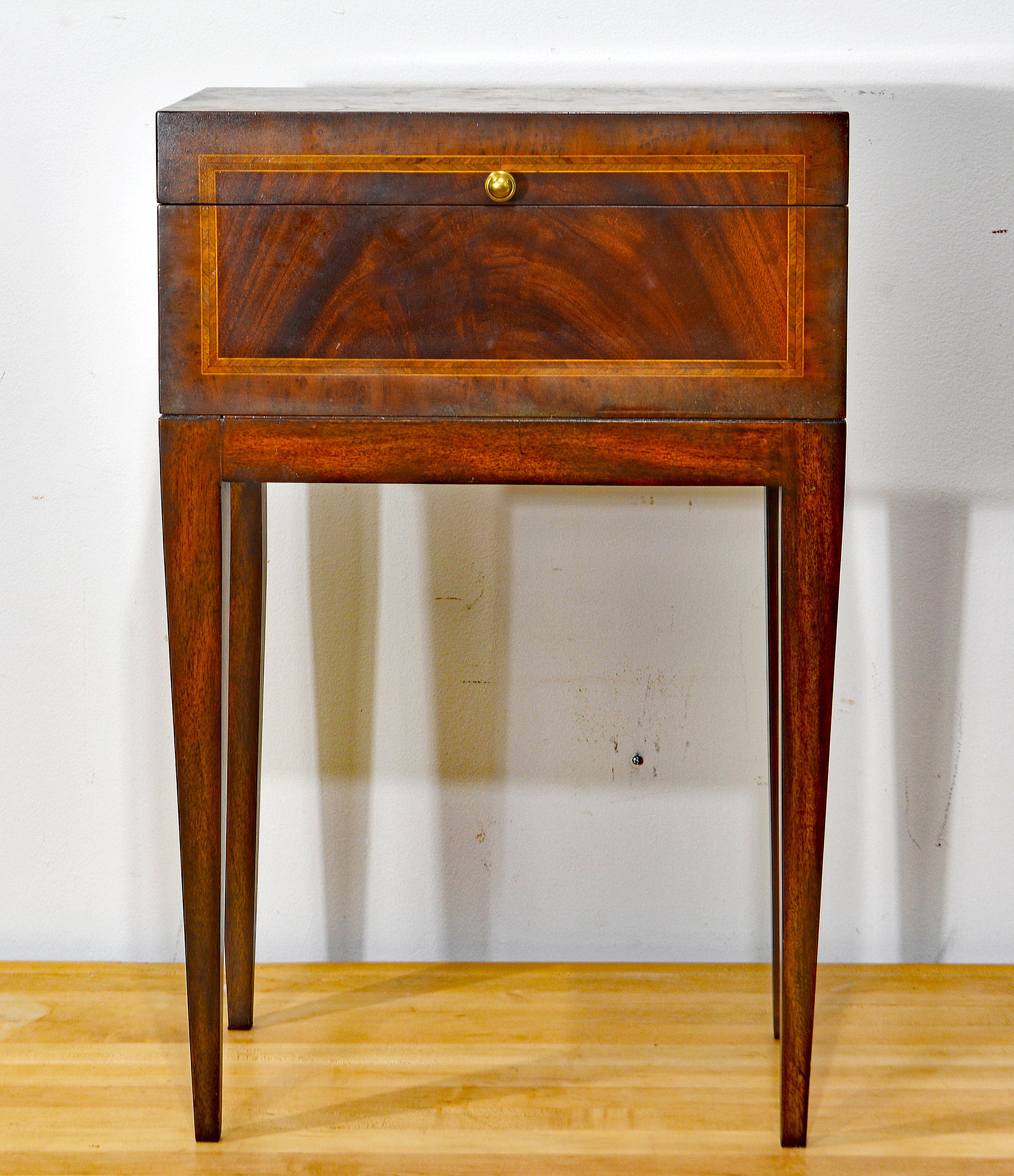 This stylish Maitland Smith mahogany side table features a top in the form of a compartment with a lid openeing up to a fully finished interior with the Maitland Smith brass mount The top and all sides are inlaid with banding and stringing of