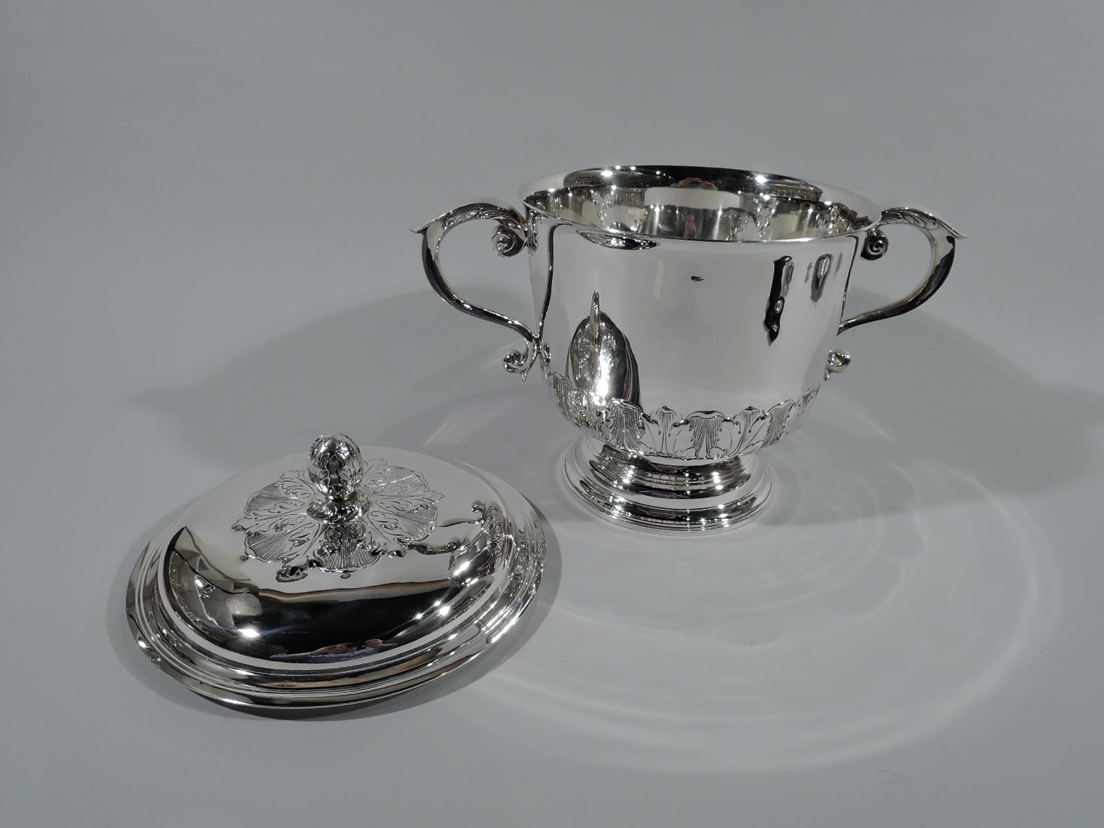 Georgian style sterling silver covered trophy cup. Retailed by Peter Guille, Ltd in New York. Urn with leaf-capped s-scroll side handles and stepped foot. Domed cover with leaf finial. Fluid leaf-and-dart border chased at base and surrounding