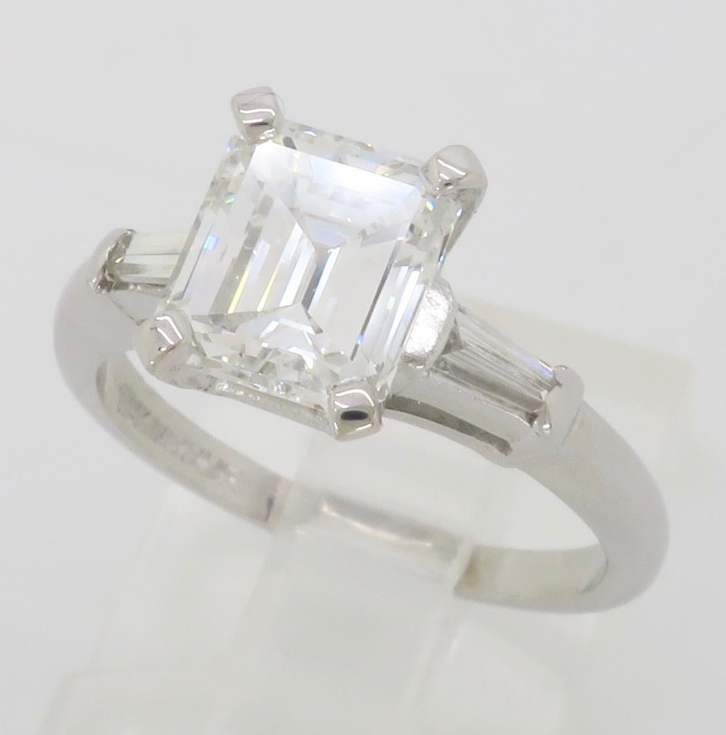 Classic GIA Certified Emerald Cut Diamond engagement ring with two tapered baguettes, made in Platinum. 

GIA Certified #2211393108
Center Diamond Carat Weight: 1.75CT
Center Diamond Cut: Emerald Step Cut
Center Diamond Color: E
Center Diamond