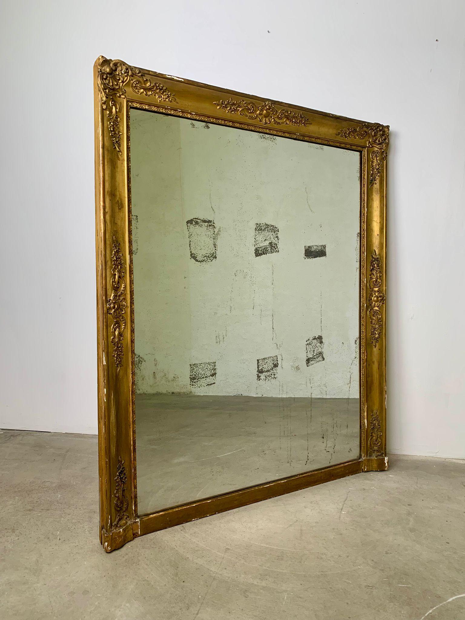 Elégant miroir de cheminée doré datant de la fin du XIXe siècle, un exemple raffiné de l'art décoratif de l'époque. La pièce se distingue par son cadre richement ouvragé, doré à la feuille d'or, aux motifs classiques et aux proportions généreuses,