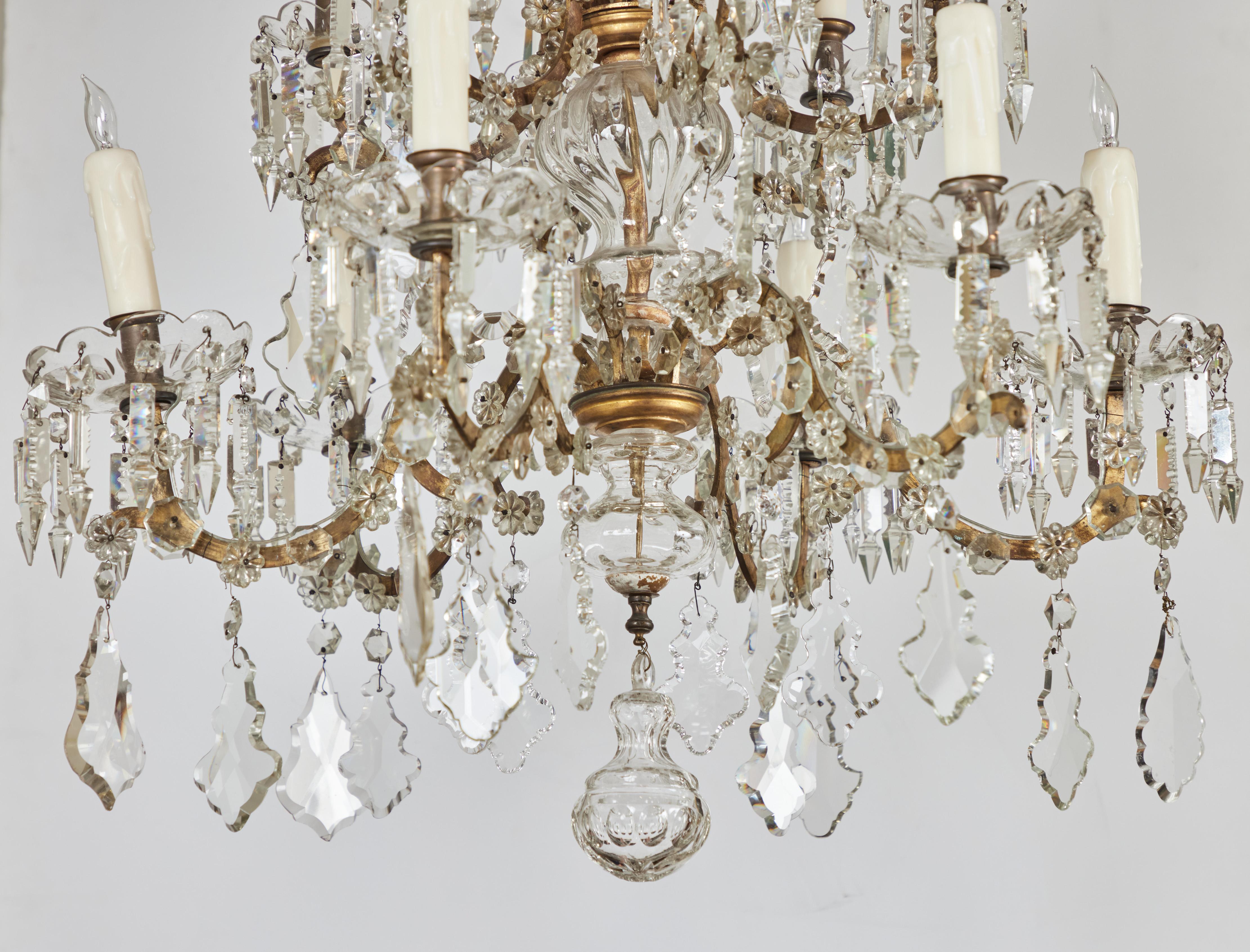 Elegant gilded metal and crystal chandelier with 12 lights. 2 Designs of scrolled placards and dramatic bobeches with hanging pendants. Wired for USA.