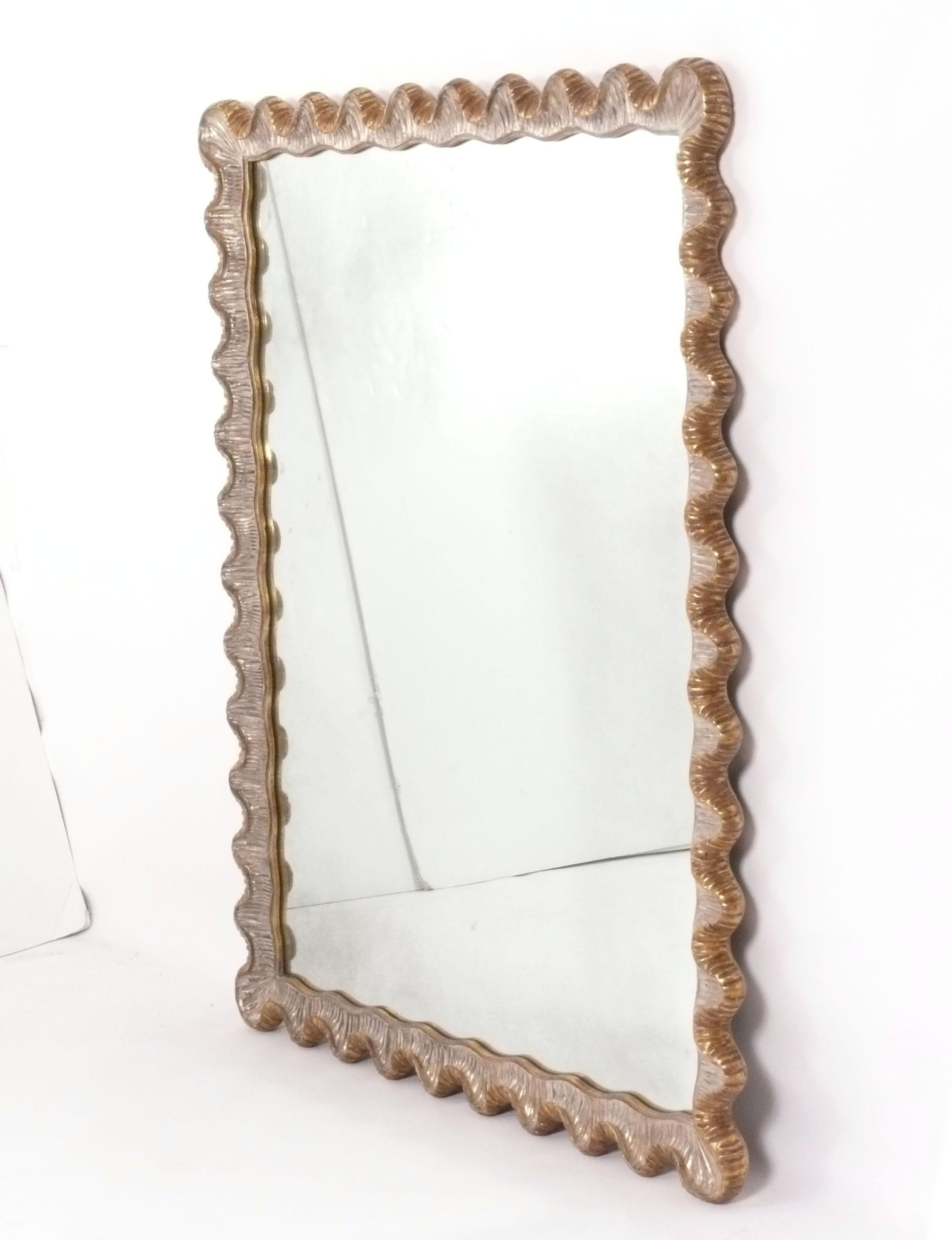 Elegant Gilt Scalloped Mirror, Italy, circa 1990s. Silver gilt in the front and gold gilt on the sides and back of the frame. Undulating curves of hand carved and gilt wood give this mirror it's elegant form. It is a large and versatile size, and