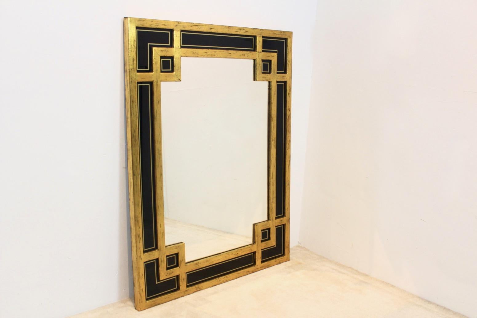 Magnifique grand miroir encadré en bois doré avec un motif graphique sophistiqué. Fabriqué en Belgique par Deknudt (marqué) dans les années 1970. Très élégant avec de magnifiques et uniques panneaux de verre noir insérés sur le côté et des feuilles
