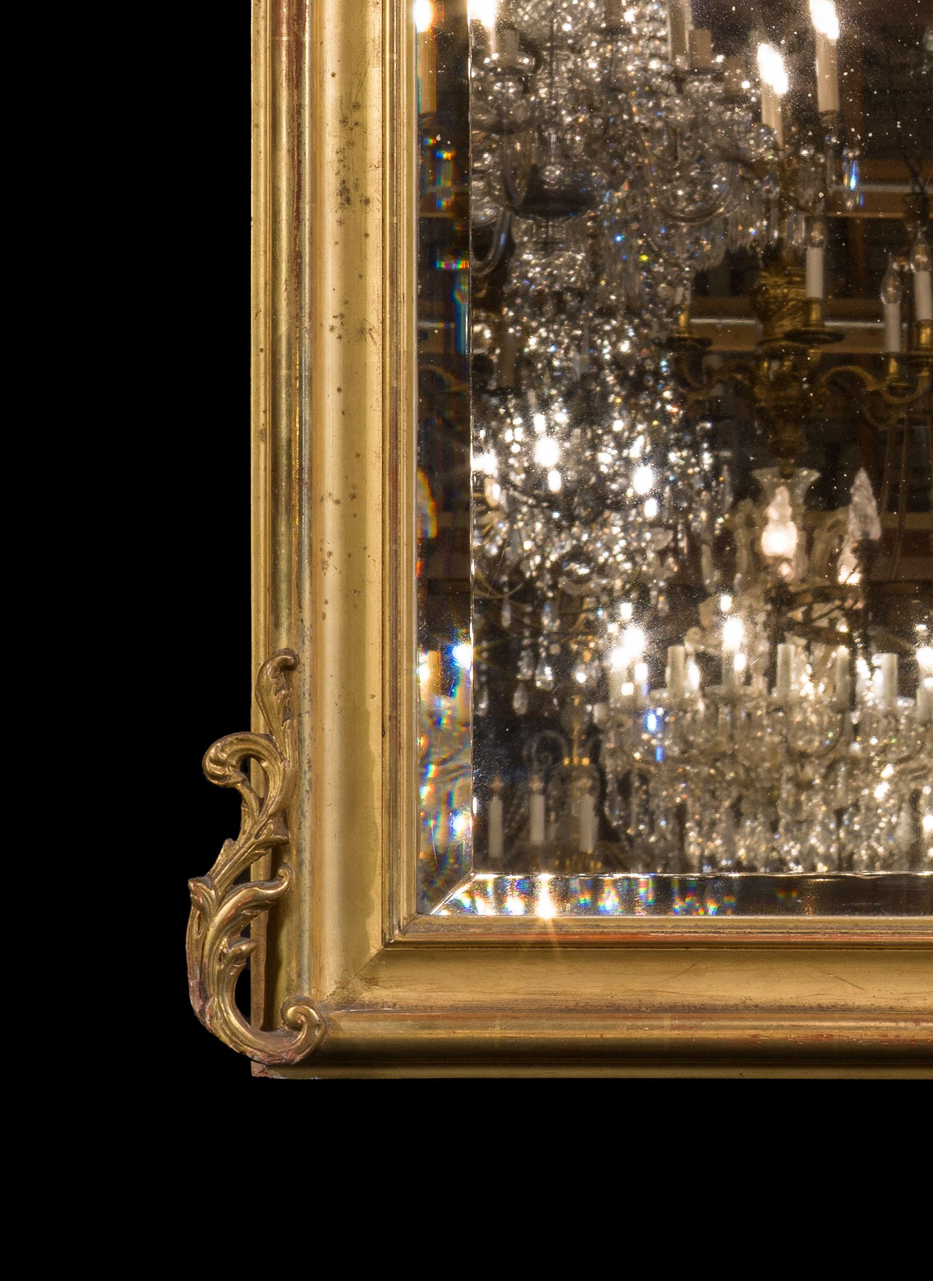 A 19th century French giltwood overmantel mirror with a Rococo foliate surmount above a cushion moulded, ogee frame. This encloses the crisp bevelled glass. A very elegant mirror.

French, late 19th century.