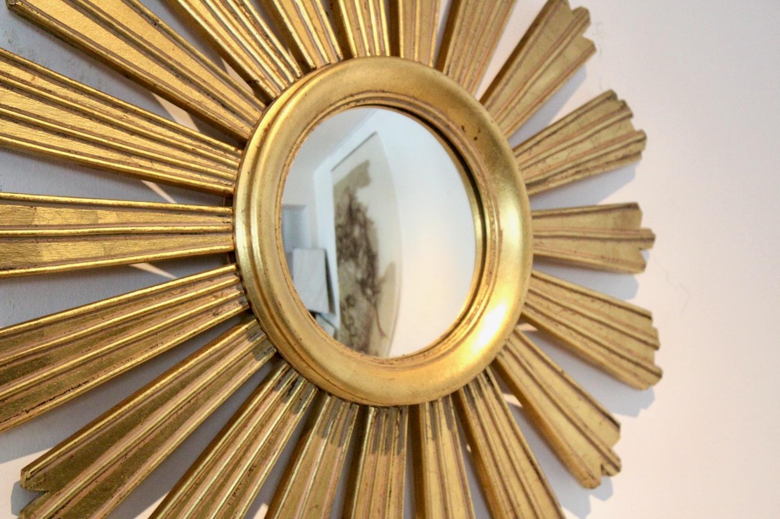 Elegant and beautiful gilded carved wooden framed Sunburst mirror made in the ‘50s in France. Very elegant and in good condition with normal wear due to use and age. Born in France during the midcentury period, this giltwood sunburst features a