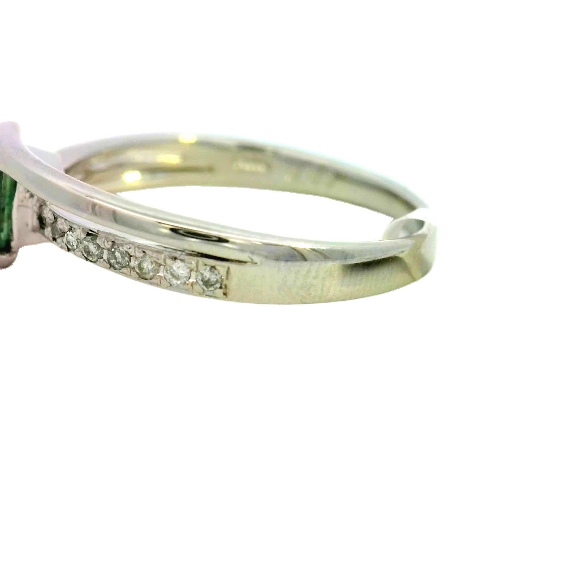 Discover the allure of this stunning green gemstone ring, designed to captivate and inspire. The unique triangular cut of the gemstone is beautifully complemented by a band adorned with sparkling diamonds, making it a perfect choice for any