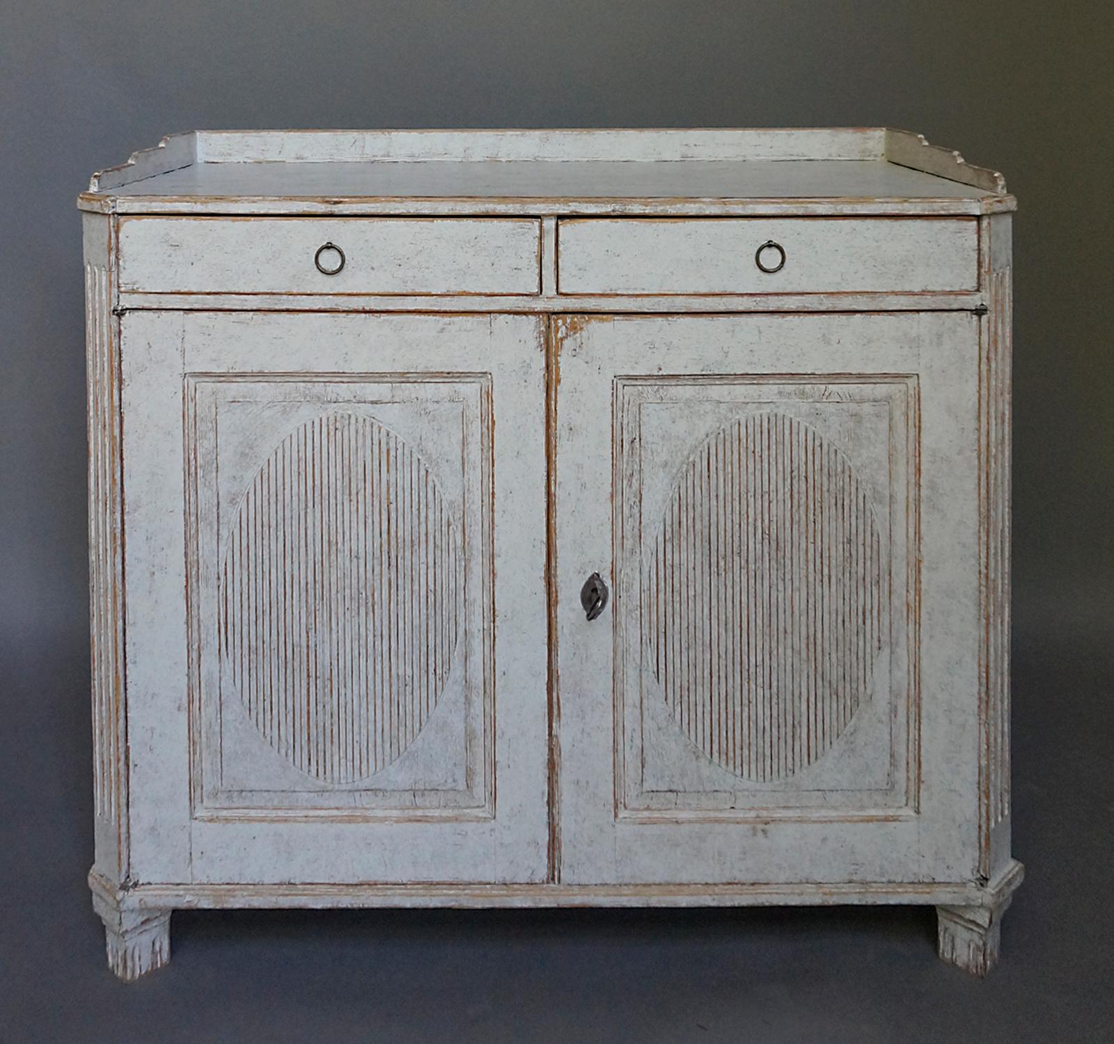 Period Gustavian sideboard, Sweden, circa 1800. Scraped back to its original surface. Two drawers over two doors with raised and reeded oval panels. Gallery top, canted corners and tapering square feet. Inside are two fixed, full-width shelves.