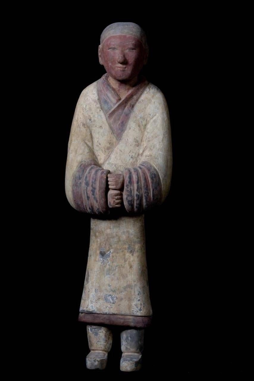Impressive terracotta warrior representing a banner bearer gripping a wooden staff with his hands (dematerialized through the ages); his gaze is serene and attentive. This beautiful figure has remains of the original polychrome painting over the