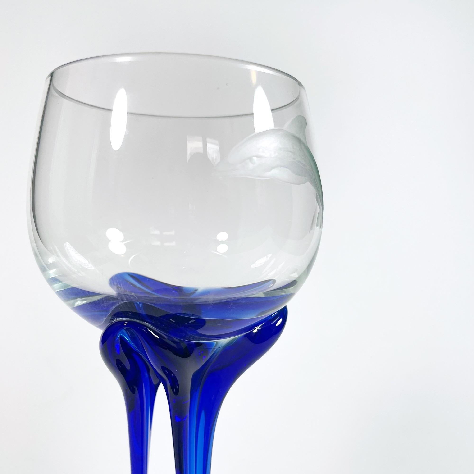Descubre el exquisito encanto de este impresionante juego de cinco copas de vino grabadas a mano, con un cautivador motivo de delfines. Fabricadas en los años 90 con cristal de Murano, cada pieza muestra la reconocida destreza de los artesanos
