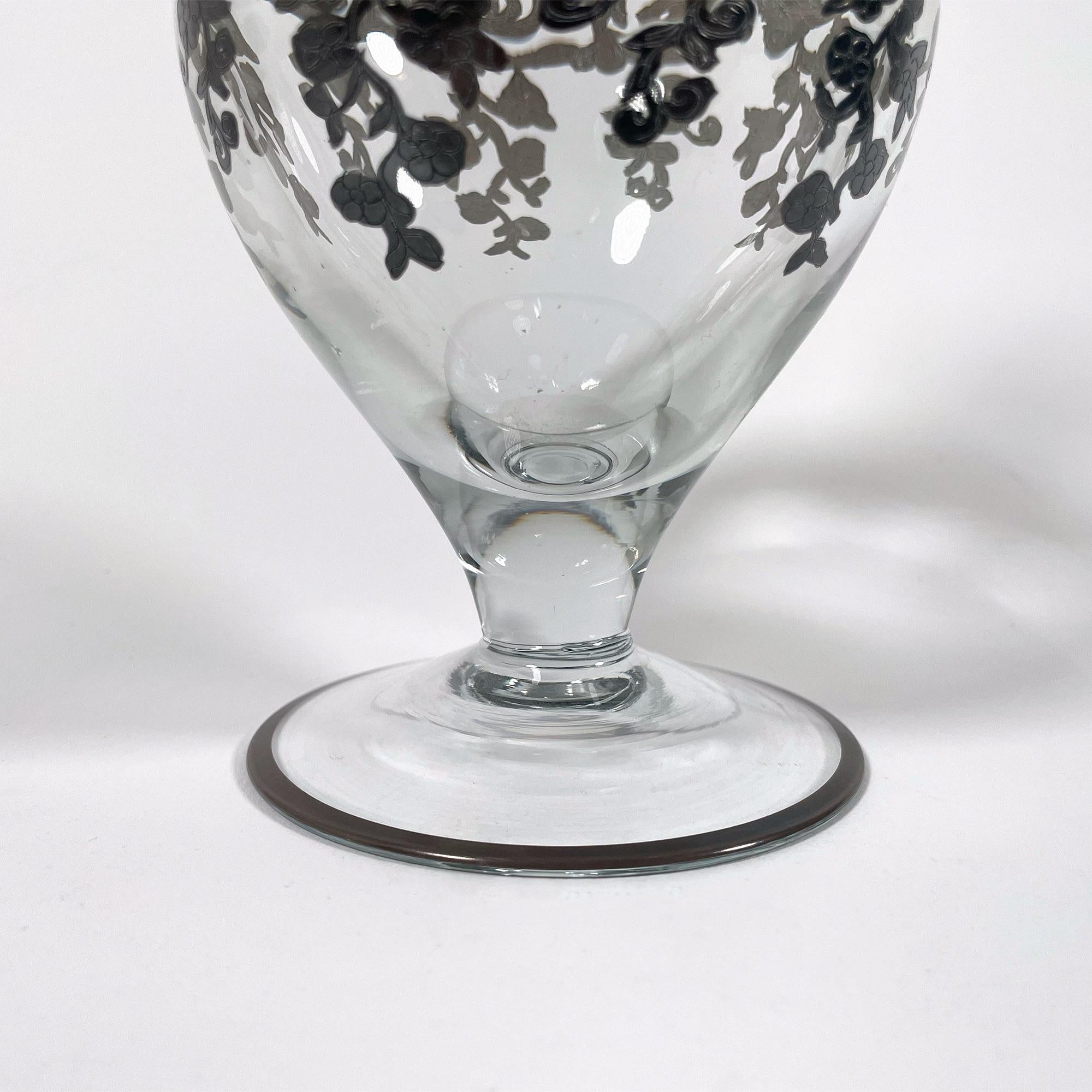 Questo squisito vaso Soliflores in vetro dipinto a mano, risalente agli anni '30, è un pezzo senza tempo dal fascino art déco. Alto 20 cm e con un diametro di 10 cm, presenta un raffinato design in vetro trasparente impreziosito da intricati