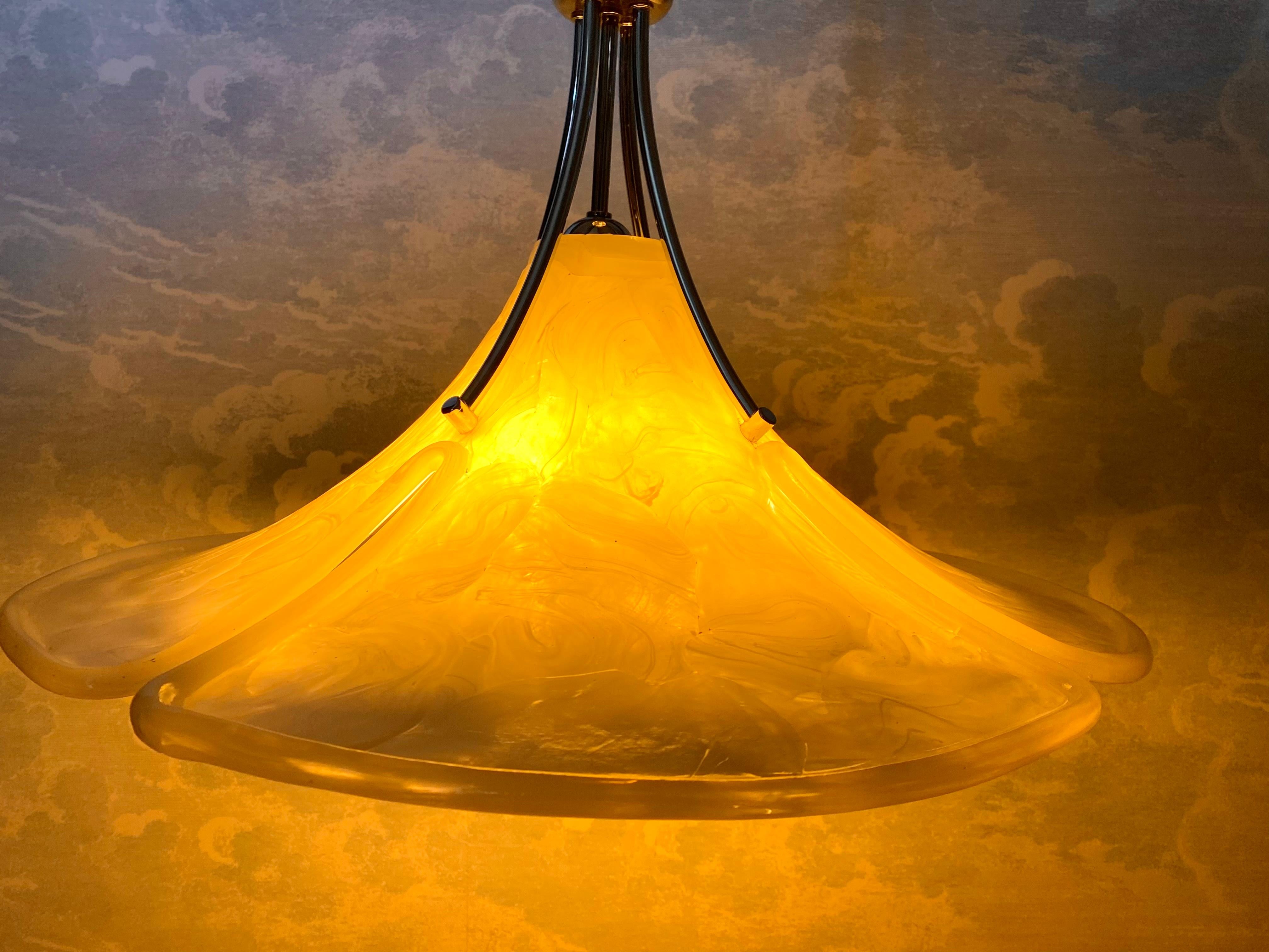 Questa lampada a sospensione regolabile in altezza ci ha incuriosito per la sua elegante fusione di stili, che unisce le curve organiche dell'Art Nouveau alle forme geometriche del movimento Art Déco. Questo mix di stili ben riuscito, insieme agli