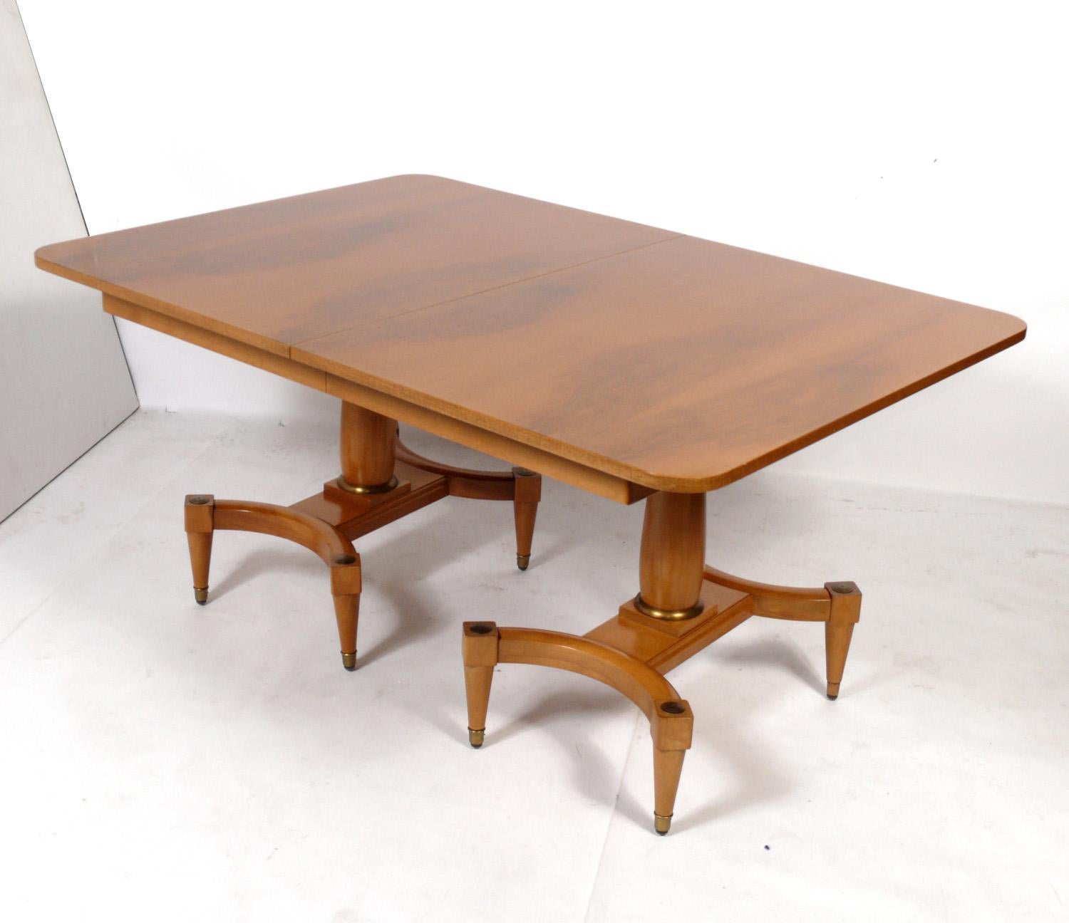 Elegant Hollywood Regency dining table, in the manner of Tommi Parzinger, American, circa 1950s. Retains warm original patina to both the wood and brass elements.