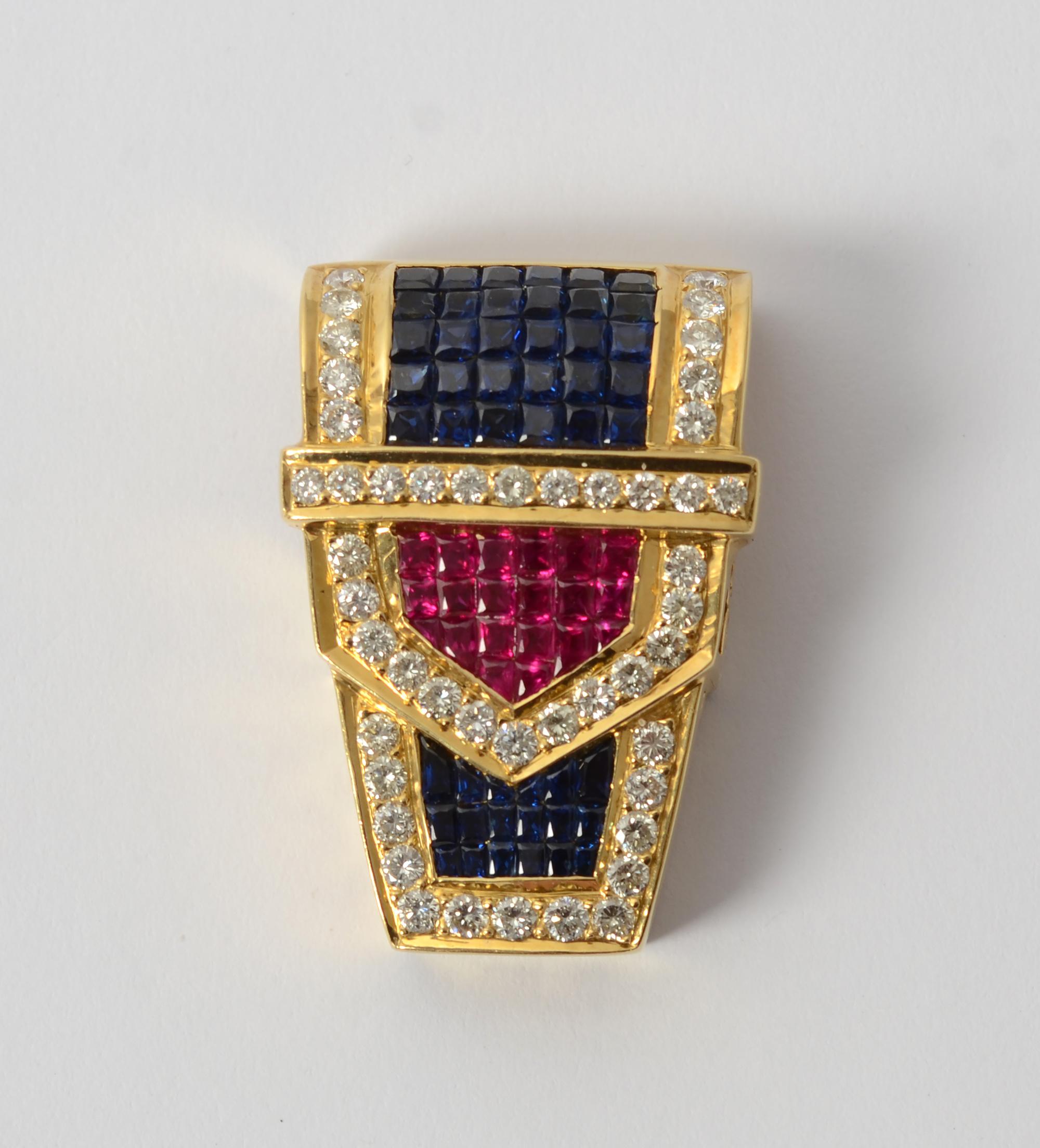 Exquisitely designed and made 18 karat gold pendant with invisibly set rubies and sapphires framed by diamonds. The pendant is in a buckle design measuring 1 1/4 inches in length and 7/8 inch at the widest.
Both the sides and backing have fine