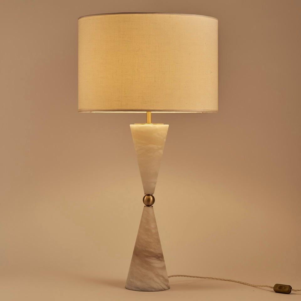 Le design de la lampe suggère un sentiment de mouvement et de dynamisme, comme si les cônes d'albâtre étaient en mouvement, créant une sensation de fluidité qui ajoute à son attrait esthétique. L'utilisation du laiton comme élément de contraste