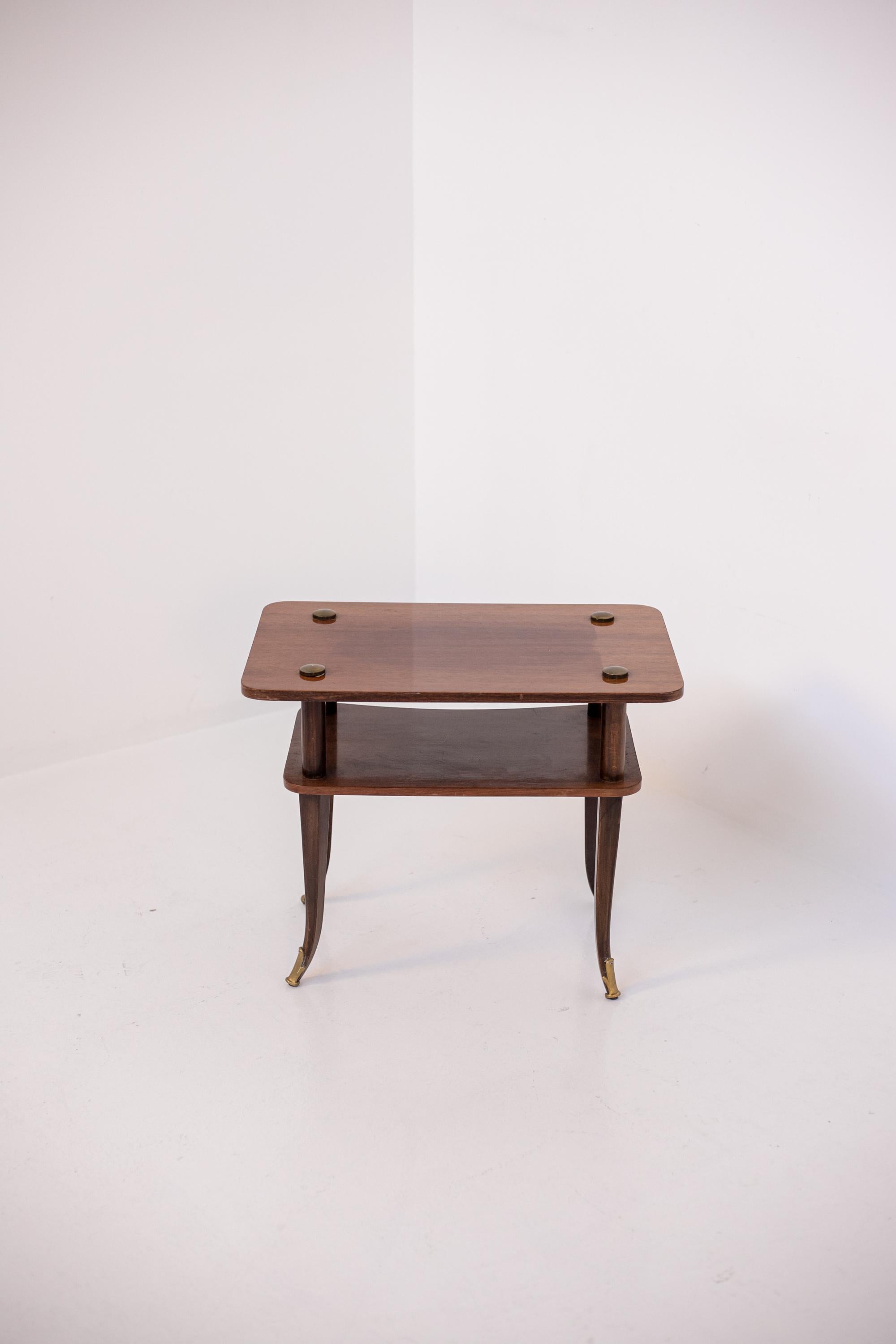 Lovely Italian wooden coffee table from the 1950s. The coffee table is made of wood with a rectangular shape. The peculiarity of the coffee table is in its realization with two shelves with its four legs slightly curved down outward. The feet of the