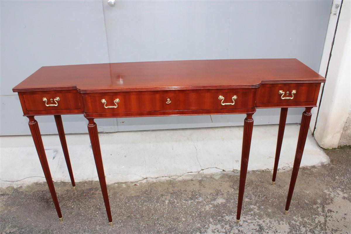 Midcentury elegant Italian console of the Ducrot manufacture in mahogany with three drawers with spiked feet with brass finishes,
Brand carved on drawer.