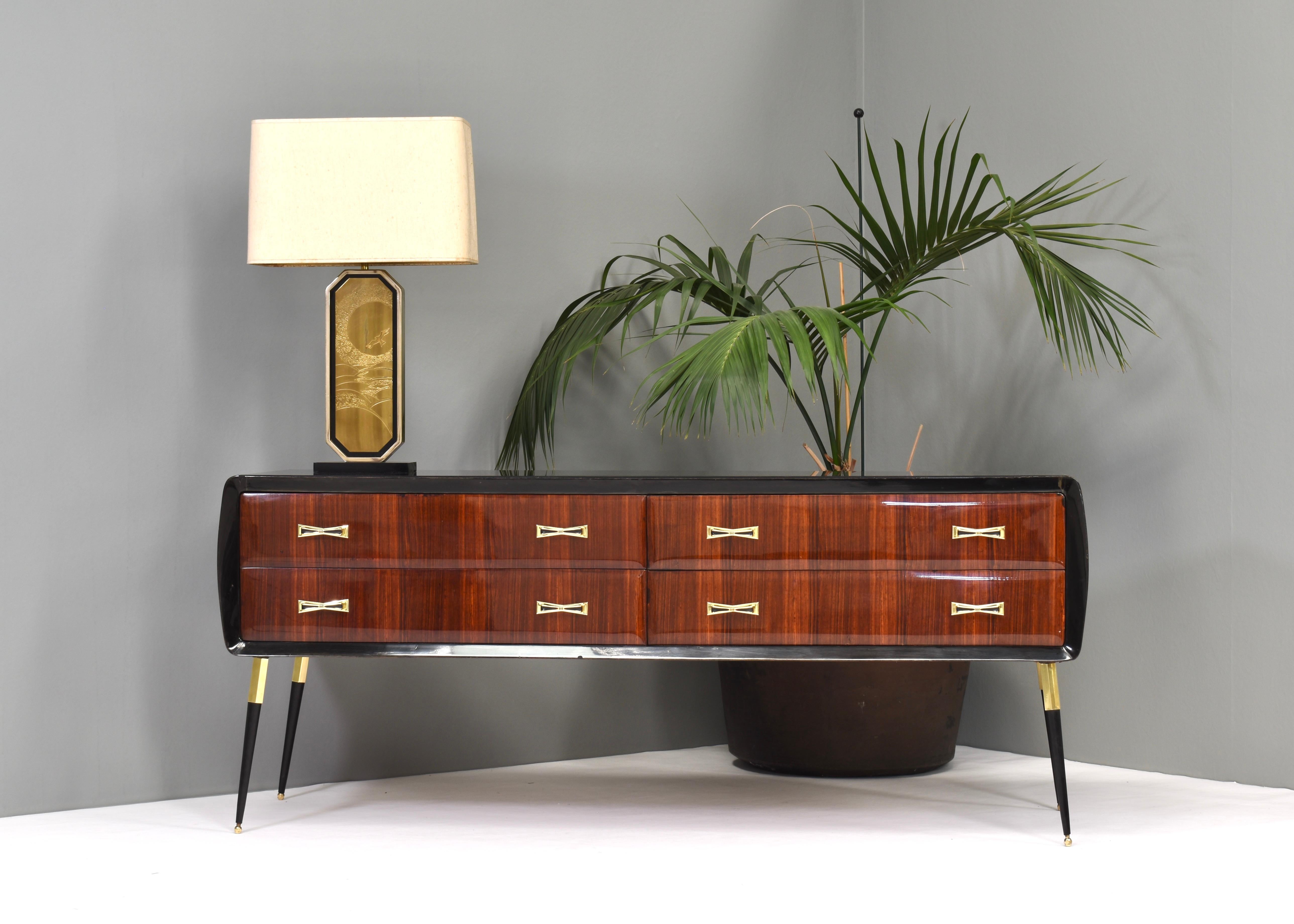 Elegant and sophisticated Italian credenza in Italian walnut, brass and glass, circa 1950.

The credenza features brass grips and legs and a new black glass top. The feet are slightly adjustable in height for leveling.

The credenza has a glossy