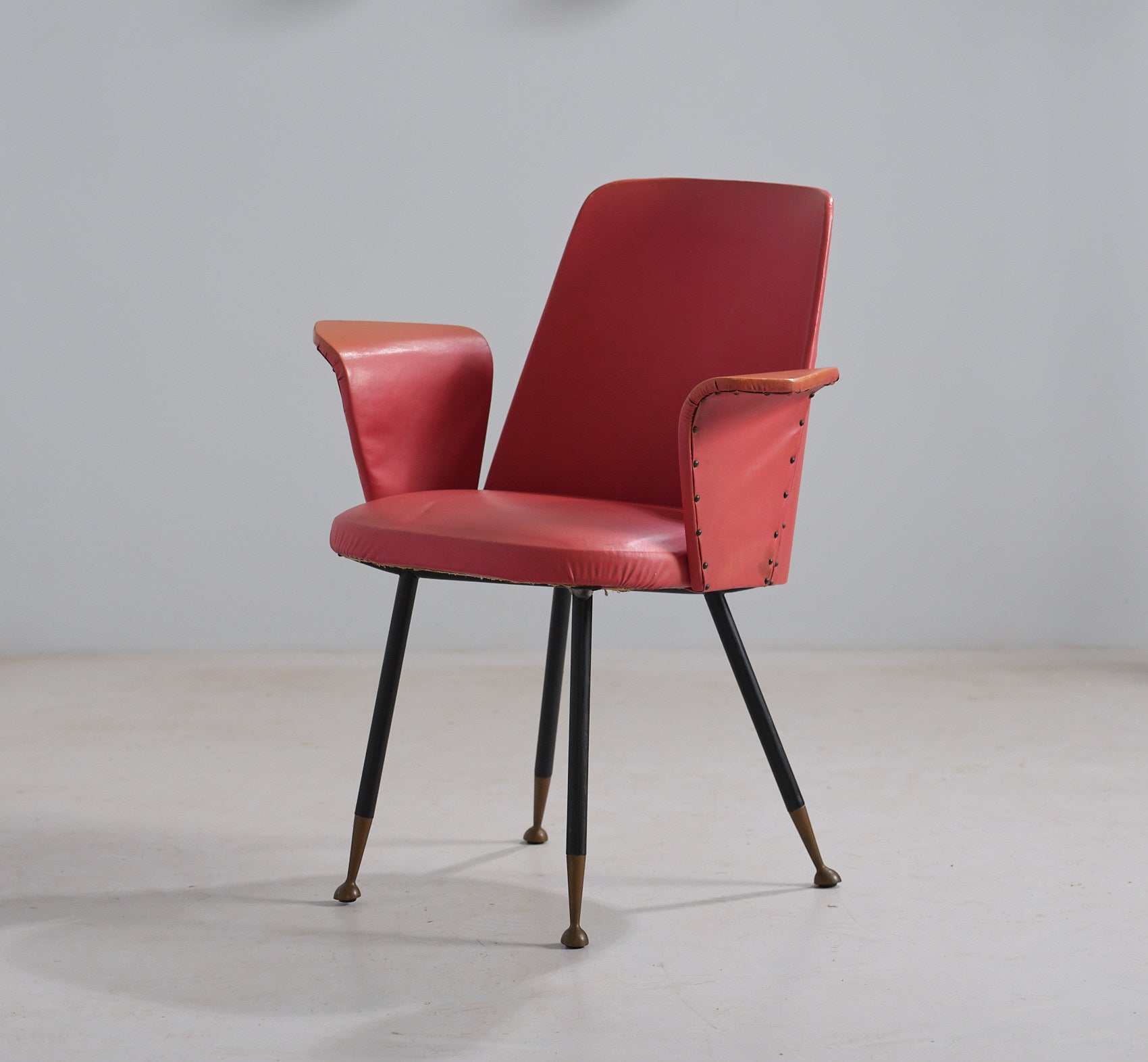 Voici une captivante chaise de bureau italienne des années 1950, incarnant un mélange de fonctionnalité et de design artistique. Ce fauteuil, au style caractéristique, présente des pieds réalisés en fer émaillé noir, coiffés d'élégantes pointes en