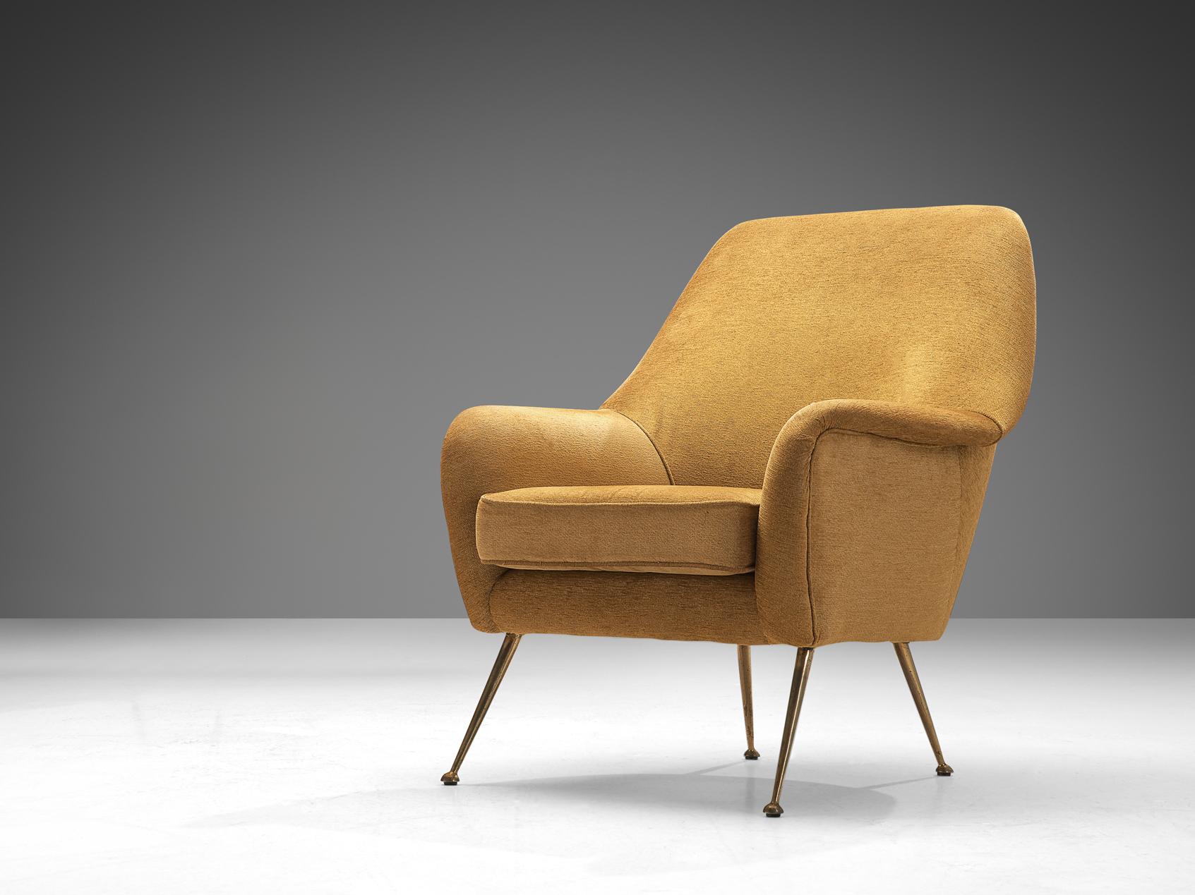 Lounge chair, fabric, brass, Italy, 1950s.

This Italian armchair is characterized by an elegant aesthetic due to its curvaceous lines and round edges. The seating area is supported by sleek outward-facing legs in brass. The back elegantly runs over