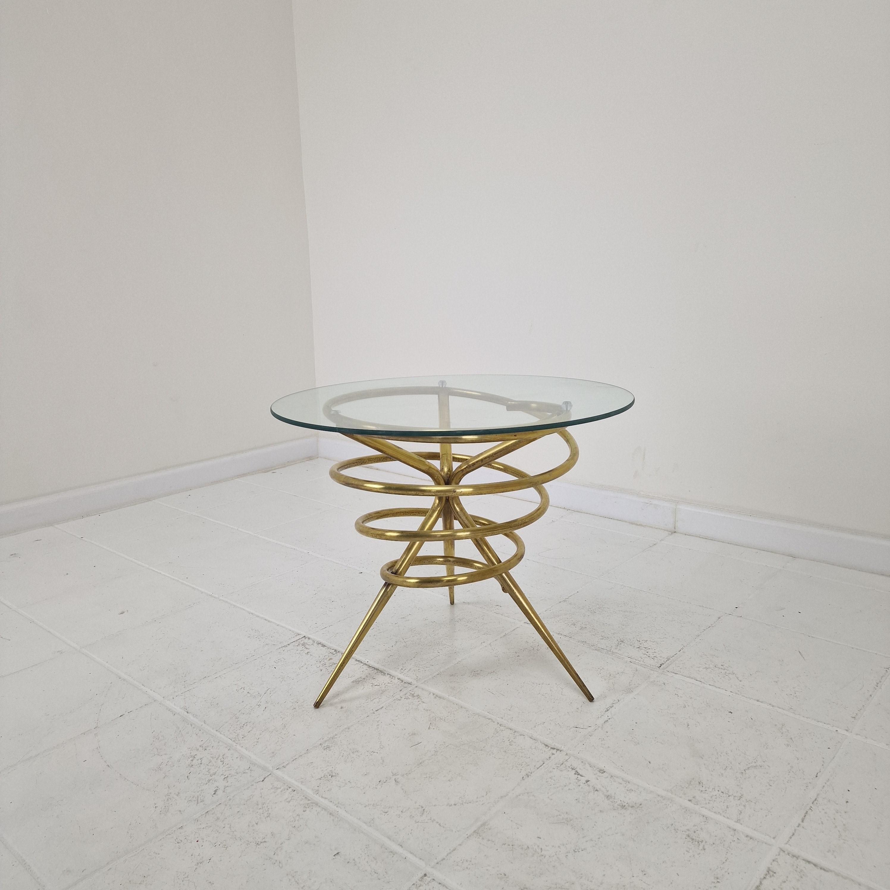 This sculptural Italian coffee or side table from the 1970s showcases a striking spiral-shaped brass base, formed by concentric rings that flow into a sleek tripod structure. 
The dynamic, almost kinetic design reflects the bold experimentation of